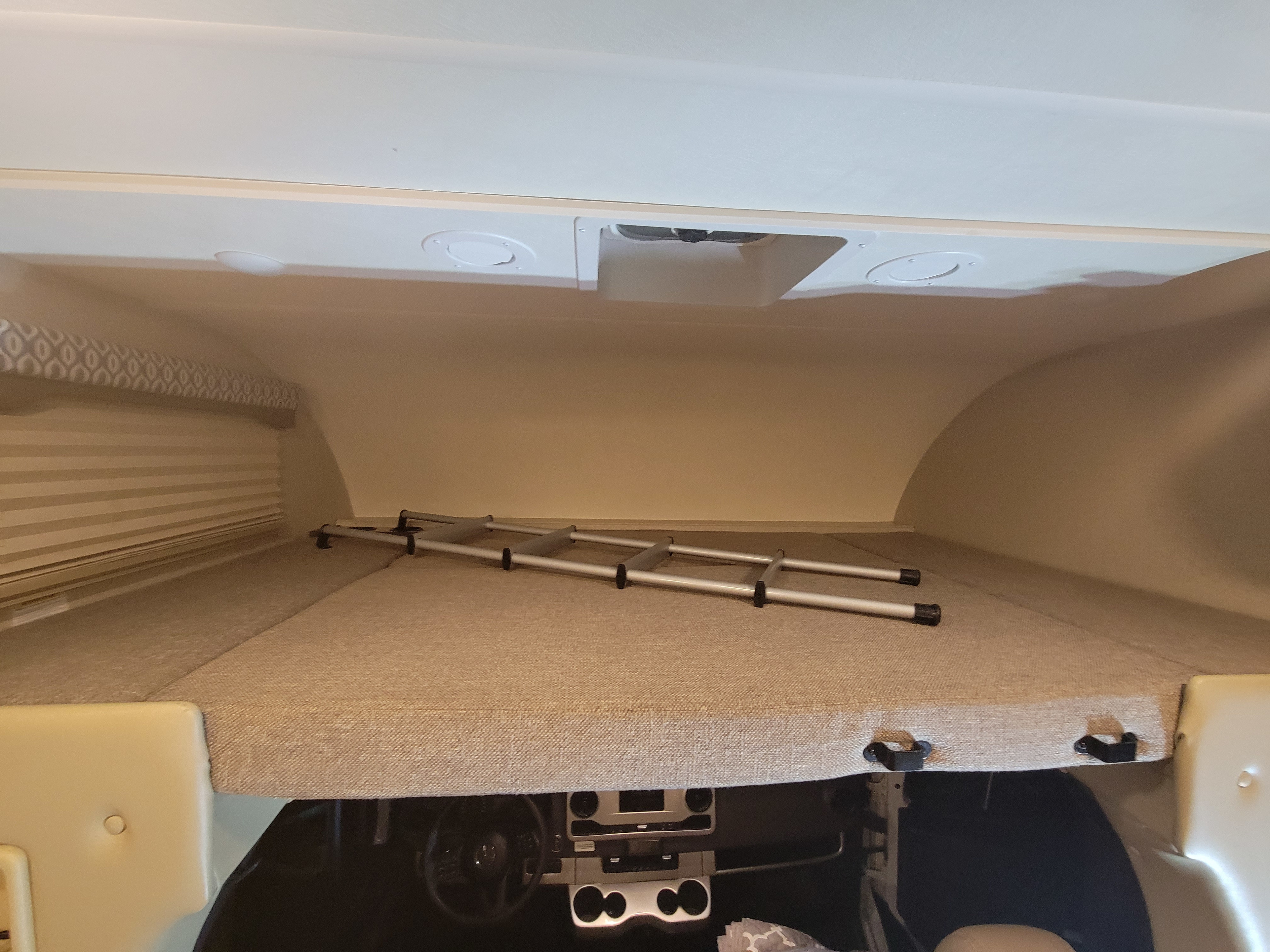RV rental's cab-over bunk, featuring a comfortable mattress, stored ladder, and window with blinds.. Thor Freedom Elite 2020
