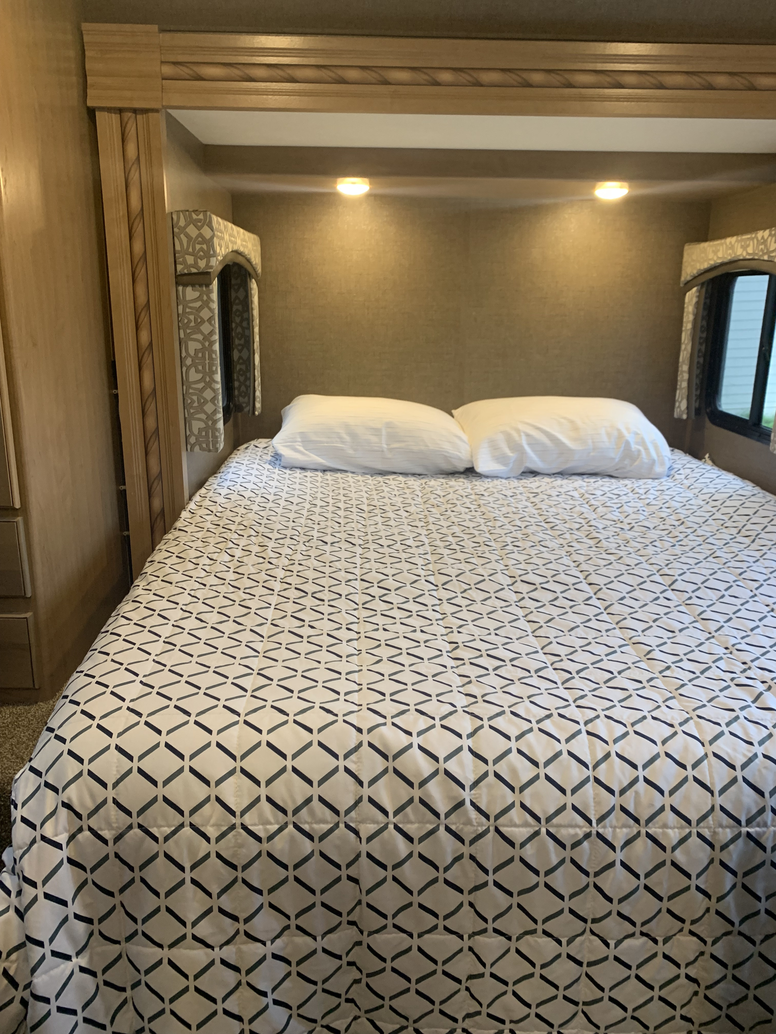 Comfortable RV rental bedroom with geometric patterned bedding and cozy lighting, perfect for travel.. Thor Motor Coach Chateau Sprinter 2018