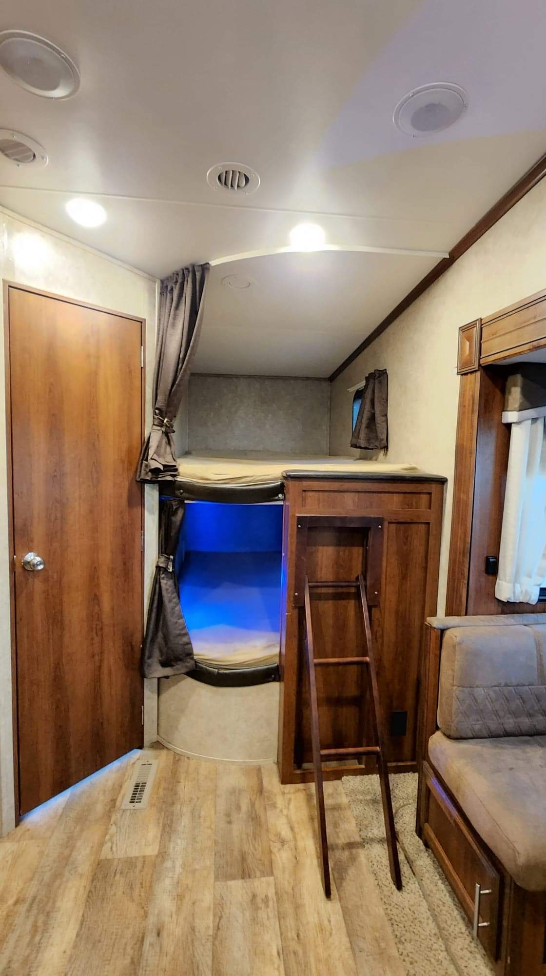 Spacious RV rental interior featuring cozy bunk beds with blue accent lighting, a ladder, and wood finishes.. Jayco Eagle HT 2018