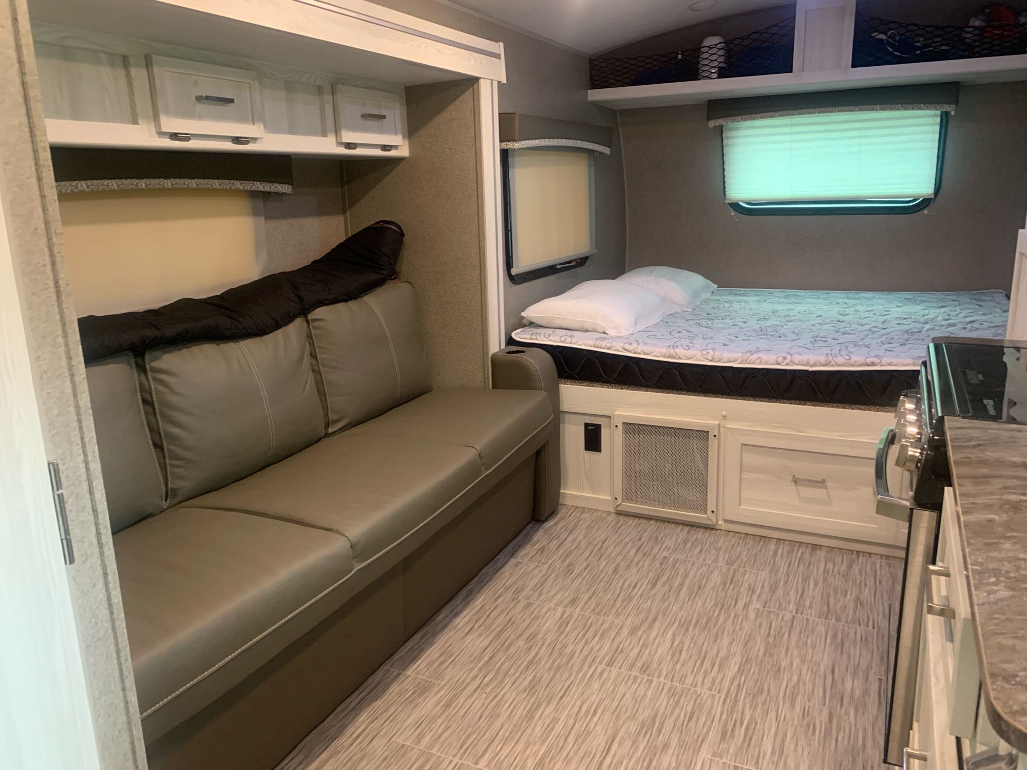 RV rental interior showcasing a sofa, a bed, and a partial view of the kitchen counter. Ideal for compact living.. Forest River Rockwood Geo Pro 2019