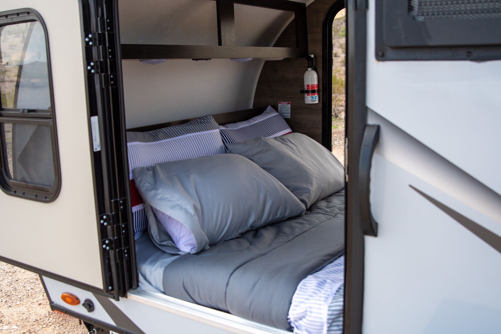 Cozy RV rental bedroom with a comfortable bed, pillows, and a visible fire extinguisher for safety on your travels.. Braxton Creek Free Solo 2022