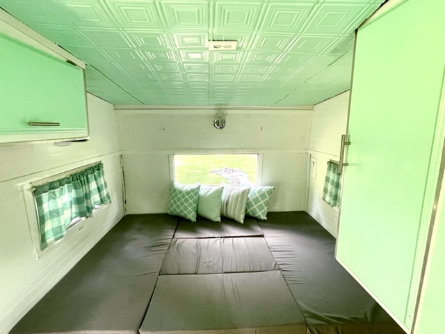 Experience comfort in this RV rental's mint green & white interior, featuring a convertible bed and stylish ceiling tiles.. Shasta Compact 1973