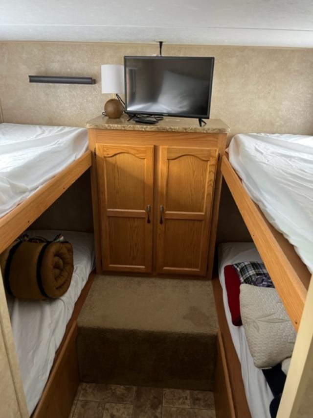 RV rental interior featuring bunk beds, a central cabinet with a TV, offering compact sleeping and entertainment.. Keystone RV Summerland 2011