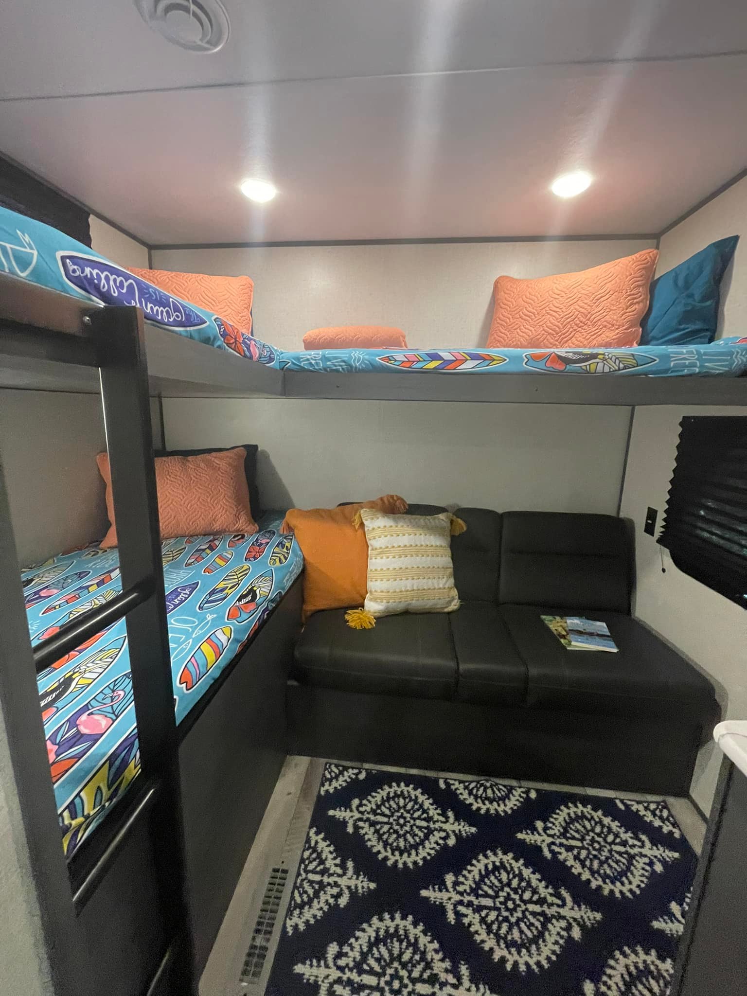 Cozy RV rental interior with bunk beds, a sofa, and vibrant surfboard bedding, perfect for family adventures.. Dutchmen Aspen Trail 2022