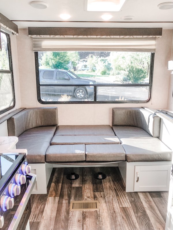 Experience comfort in this RV rental's gray dinette, converting to a bed, with a scenic window view.. Keystone RV Bullet Ultra Lite 2019