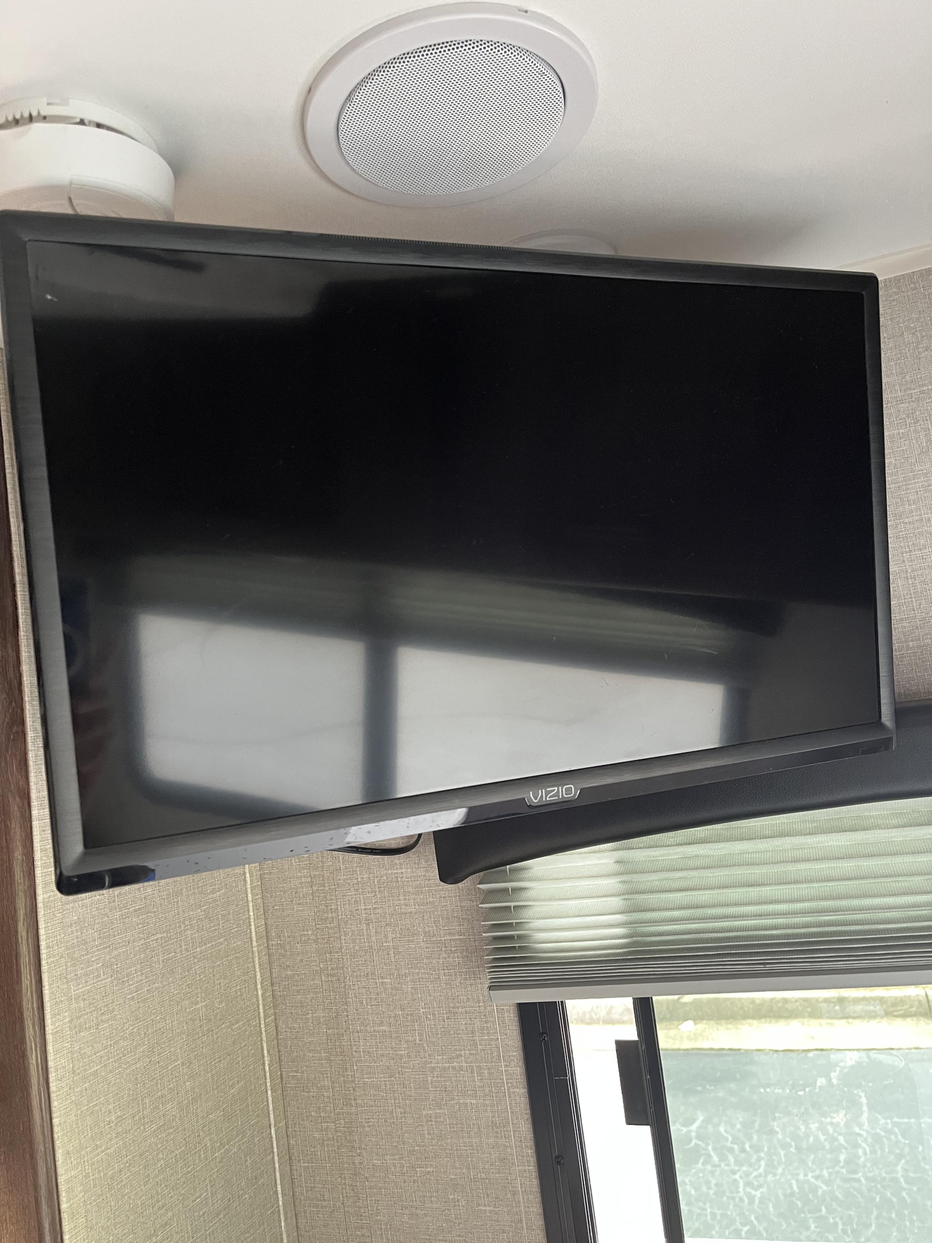 RV rental interior featuring a Vizio TV mounted high, with a ceiling speaker and smoke detector above, and blinds below.. Travel Lite Falcon 2019