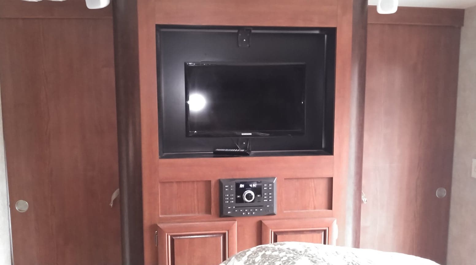 RV rental bedroom features a built-in TV, stereo, and ample wooden wardrobe storage. Compact, functional RV interior.. Forest River Salem 2015