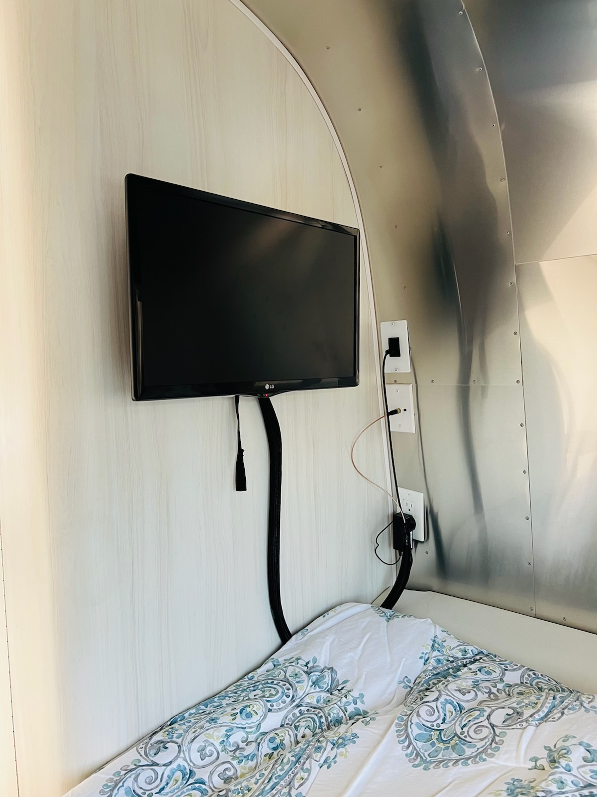 RV rental: A compact interior with a TV mounted above a comfortable bed and sleek metallic walls.. Airstream Bambi 2020