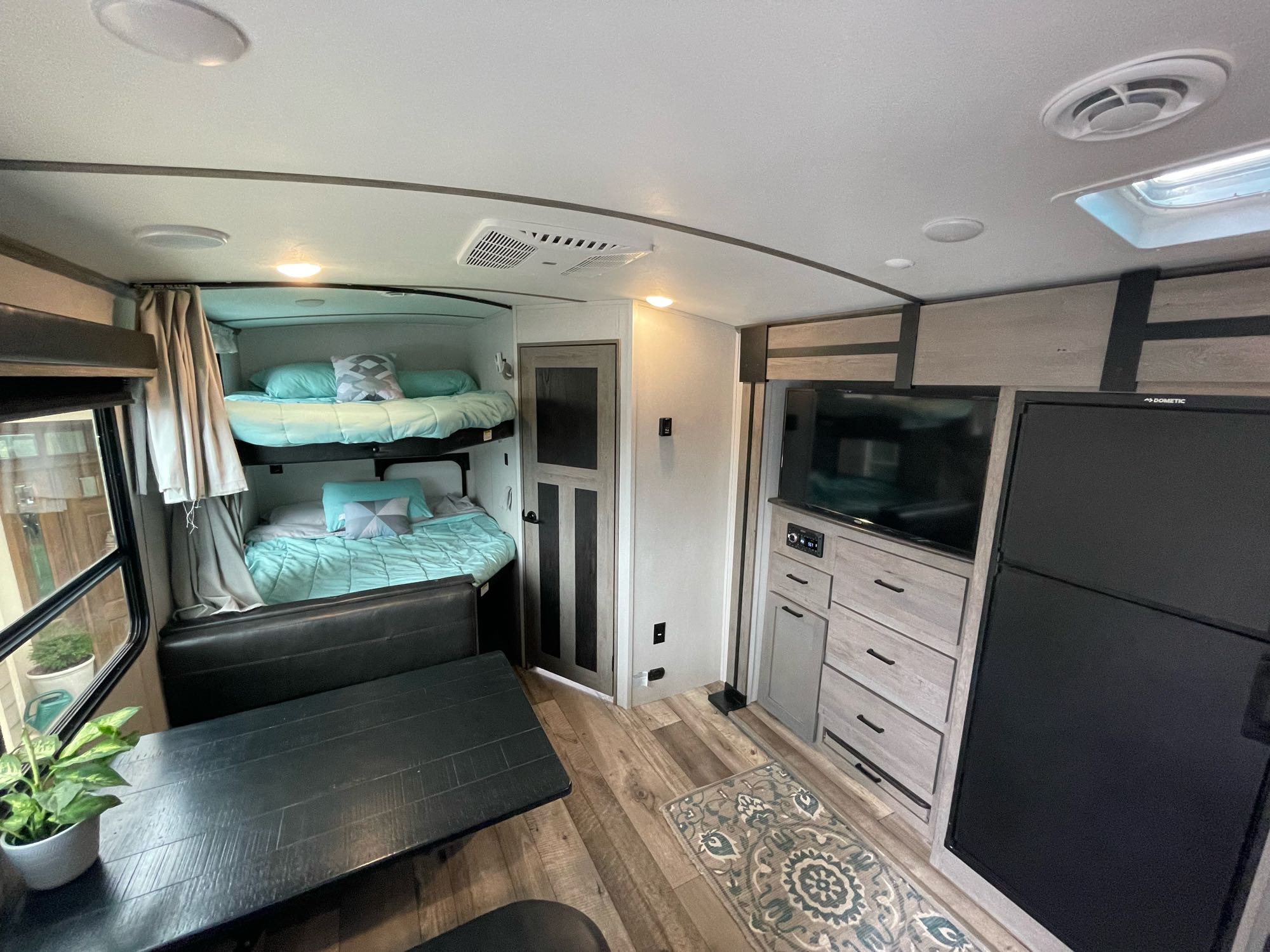 RV rental interior featuring bunk beds, a dining area, and an entertainment center, creating a cozy living space.. Keystone RV Outback Ultra-Lite 2021