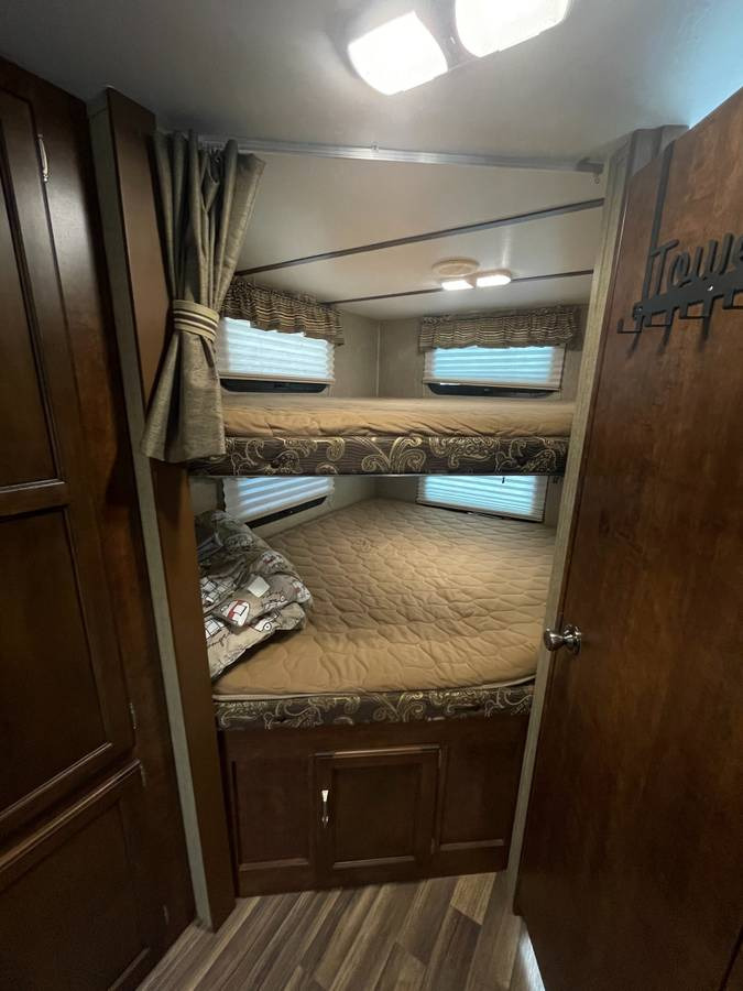 Cozy RV rental bunkhouse with two beds, privacy curtains, and windows, ideal for family travel.. Keystone RV Outback Ultra-Lite 2016