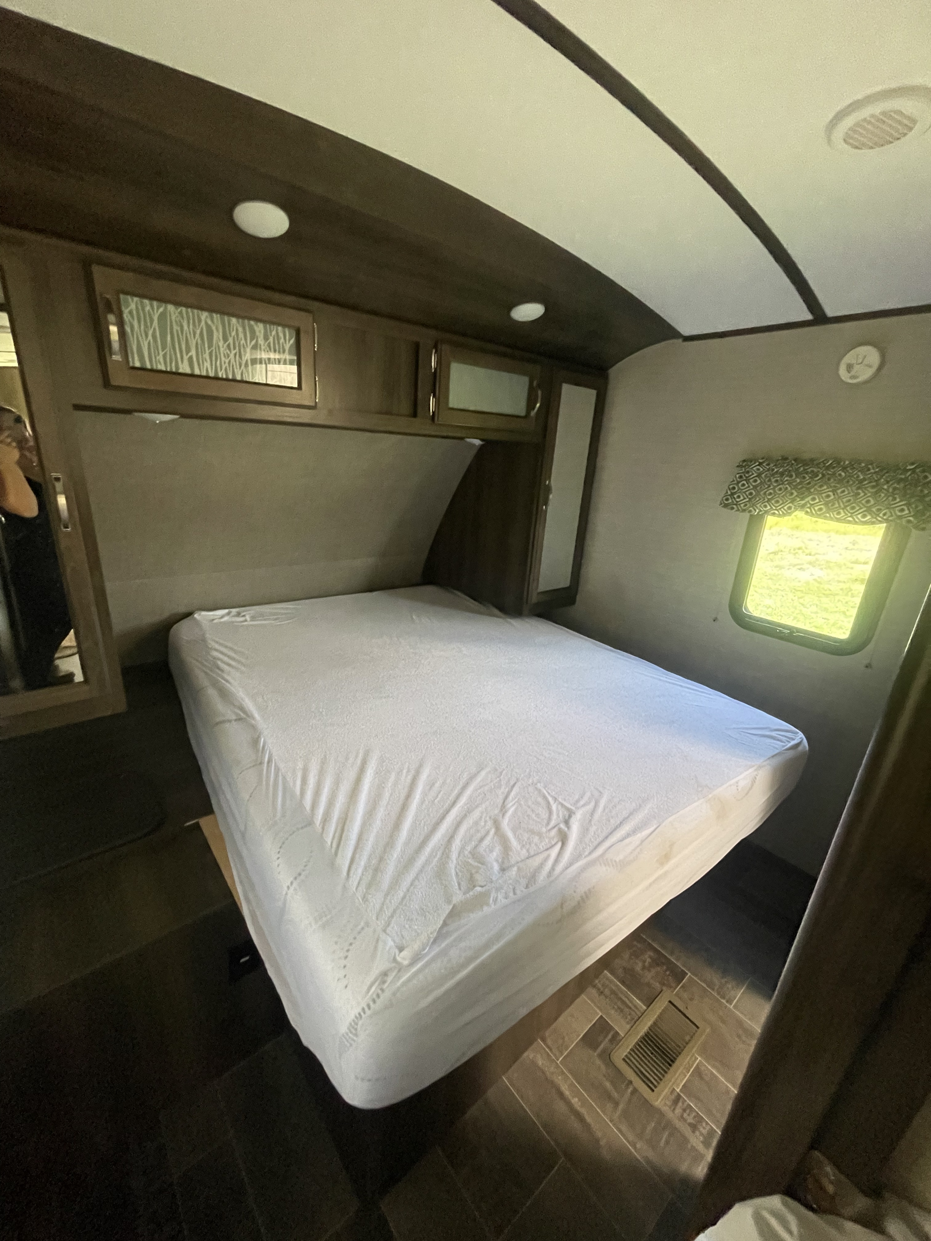 Comfortable RV rental bedroom with a bed, white mattress cover, overhead storage, and window, perfect for your travel.. Keystone RV Bullet Premier 2019