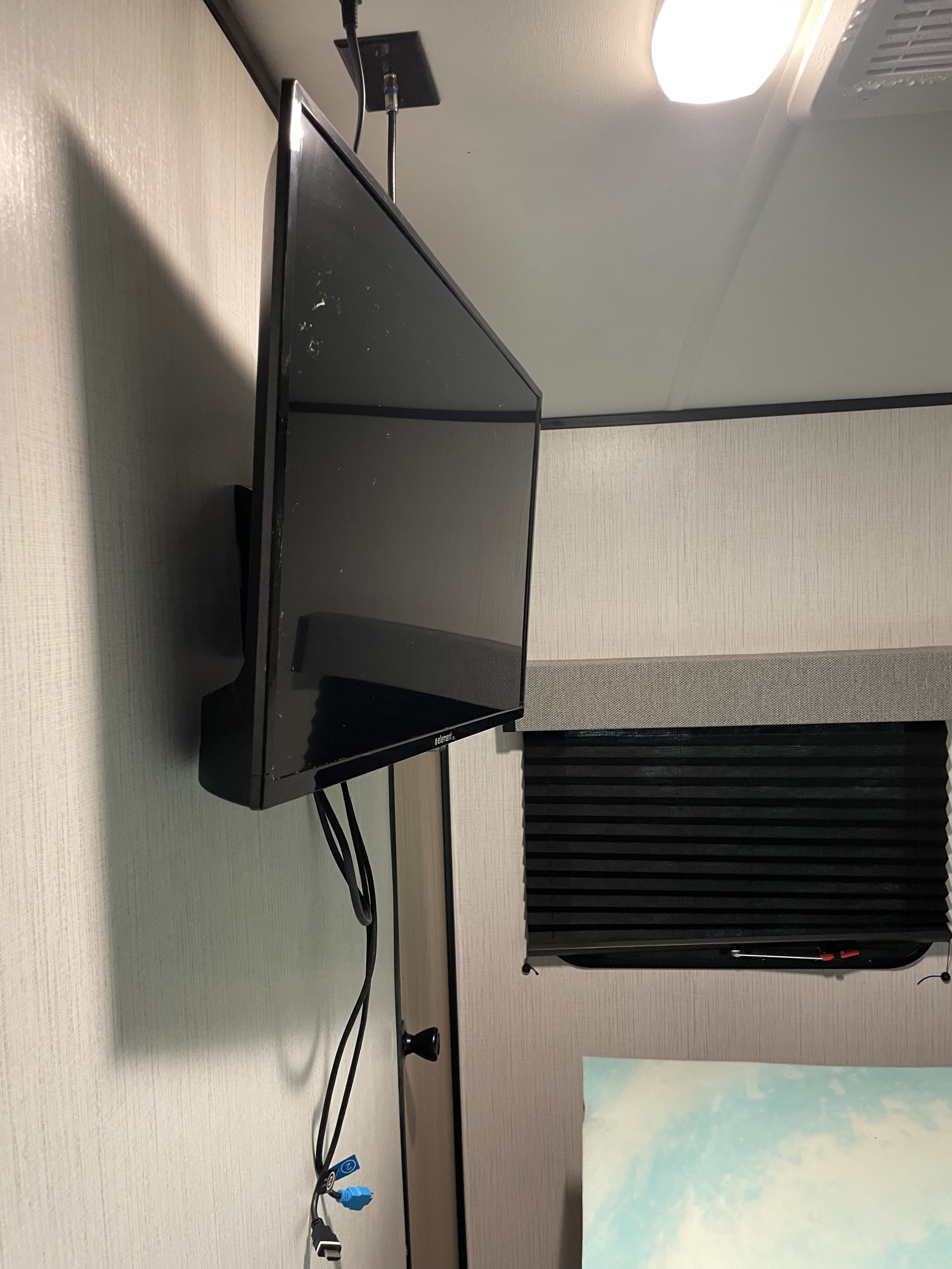 Inside an RV rental: a wall-mounted TV with cables, window blinds, and overhead light fixture, providing entertainment.. Cruiser Rv Corp Radiance 2022