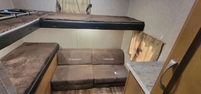 RV rental interior features multiple bunk beds and a comfortable Catalina sofa, optimizing compact space for travel.. Coachmen Catalina 2019