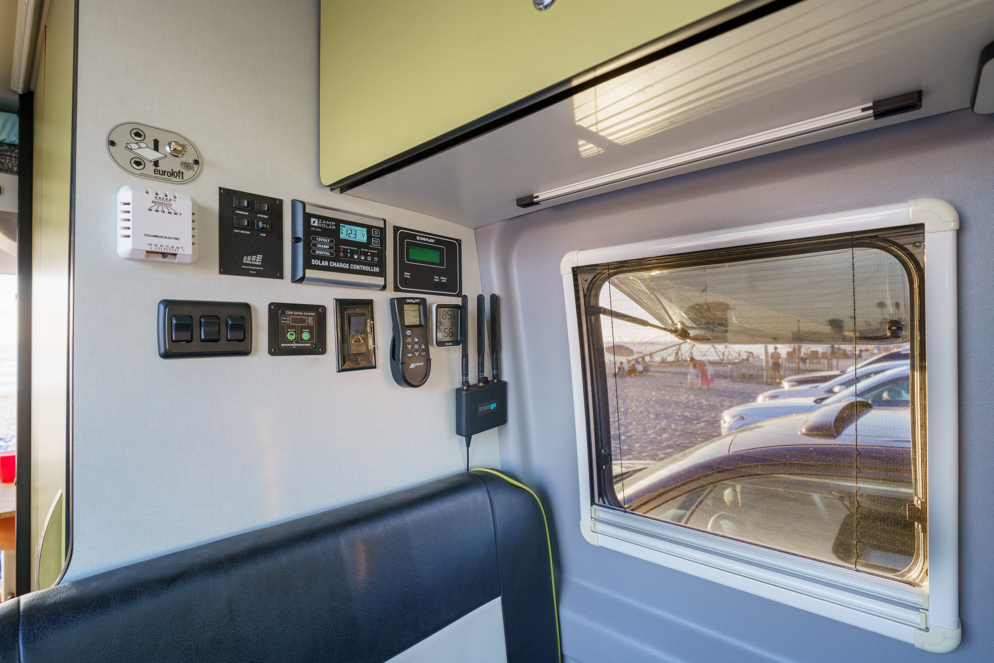 RV rental interior: Control panel displays for solar, inverter, HVAC, and Euroloft bed. Mobile internet and beach window view.. Winnebago Revel 2019