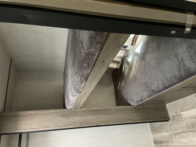 Compact bunk beds in an RV rental, with gray patterned bedding and light wood-look interior. A cozy sleeping area.. Gulf Stream Amerilite 279BH 2021