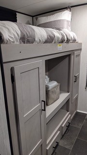 Modern RV rental interior featuring a cozy bunk bed over integrated storage cabinets and drawers, ideal for camping trips.. Heartland RVs Mallard 2022