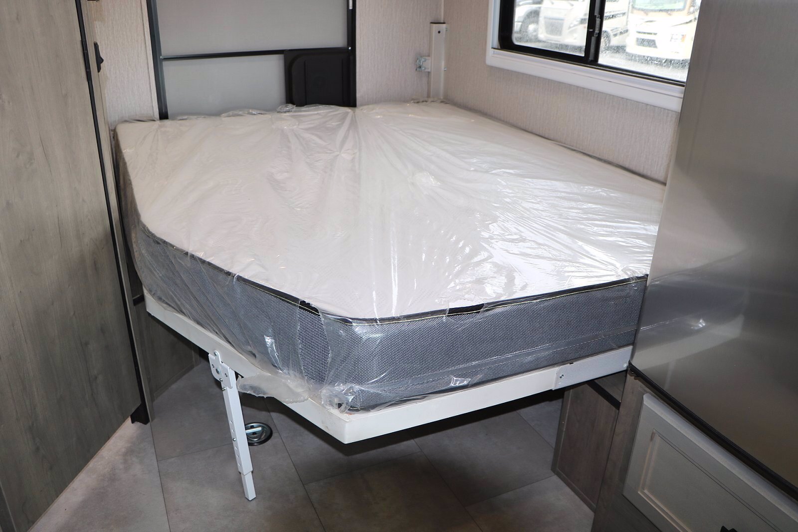 Clean RV rental interior featuring a new, plastic-wrapped mattress on a fold-out bed frame, ready for your trip.. Forest River Coachmen Cross Trail XL 2022