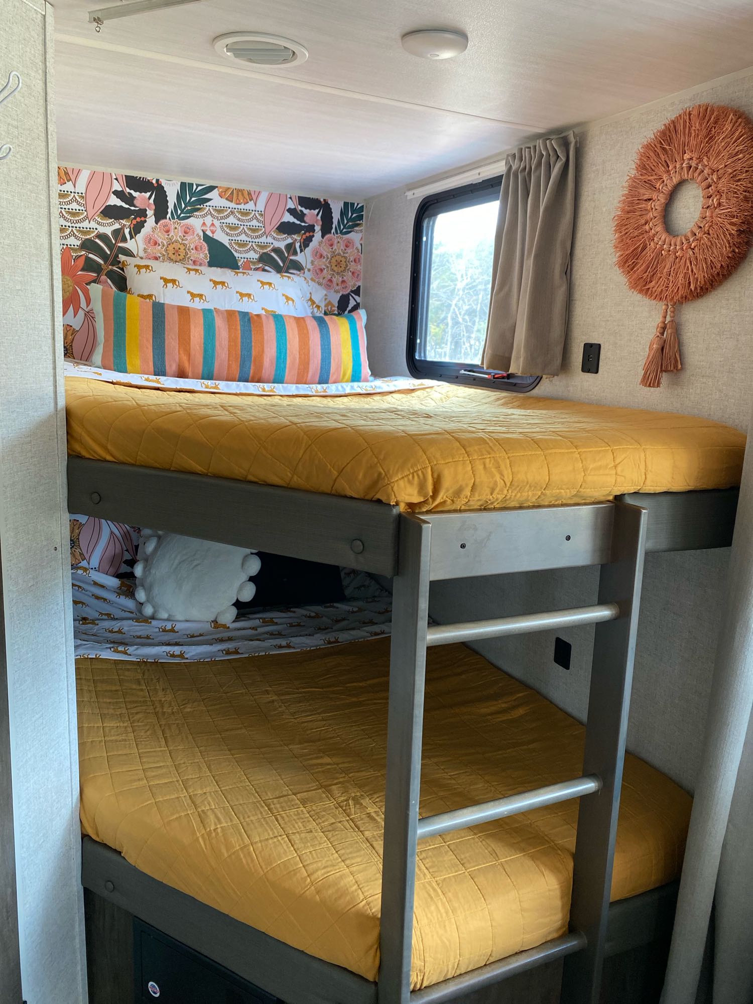 RV rental: Bright, decorated bunk beds with floral wallpaper, striped pillow, and yellow quilts create a cozy camper interior.. Forest River Wildwood X-Lite 2020