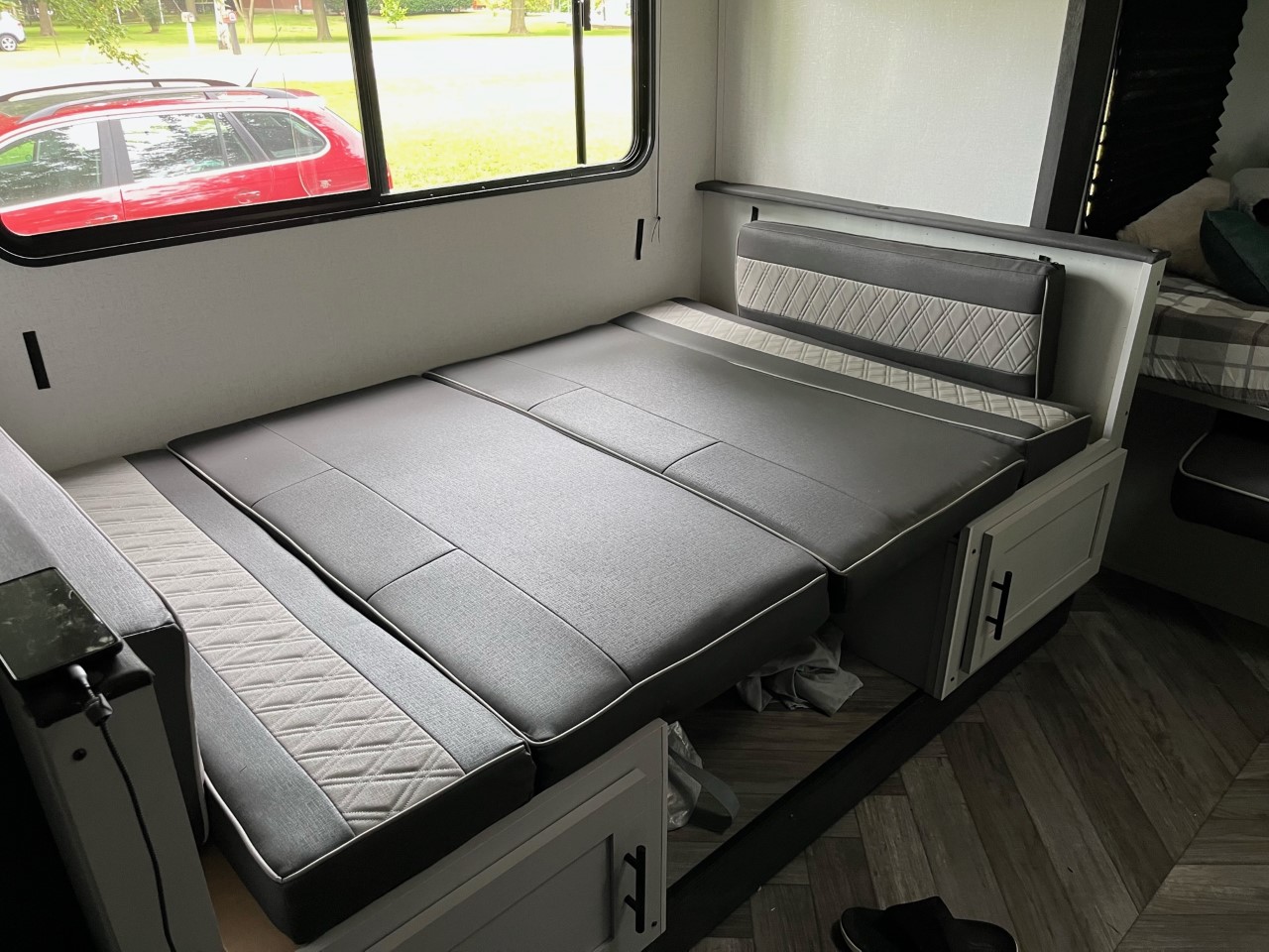 RV rental: Dinette converted to a comfy bed with grey cushions & quilted accents, beside a window view.. Forest River Wildwood FSX Plantium 2022