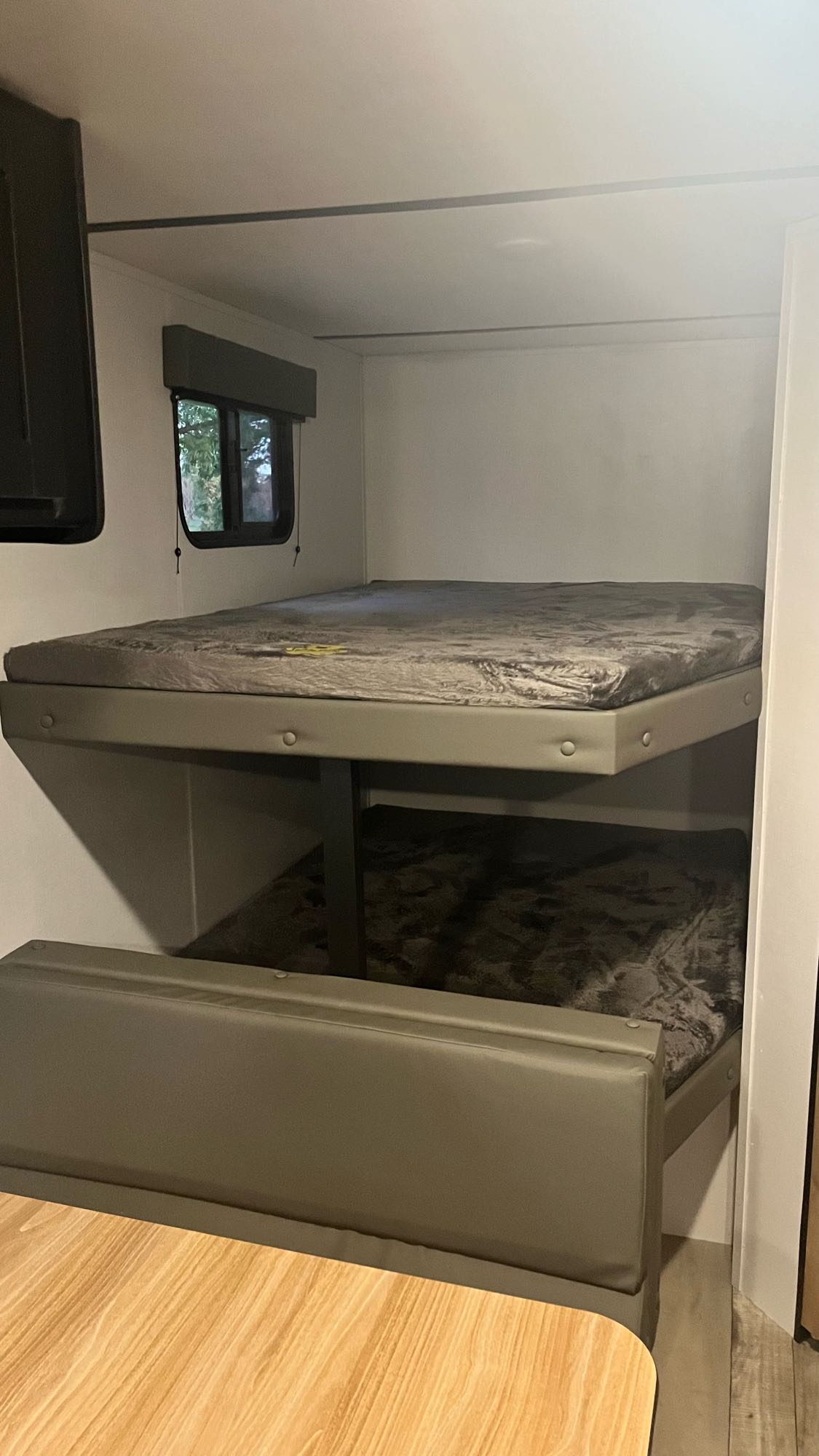 Inside an RV rental: cozy bunk beds, a window, and a comfortable dinette space.. Keystone RV Springdale 2022