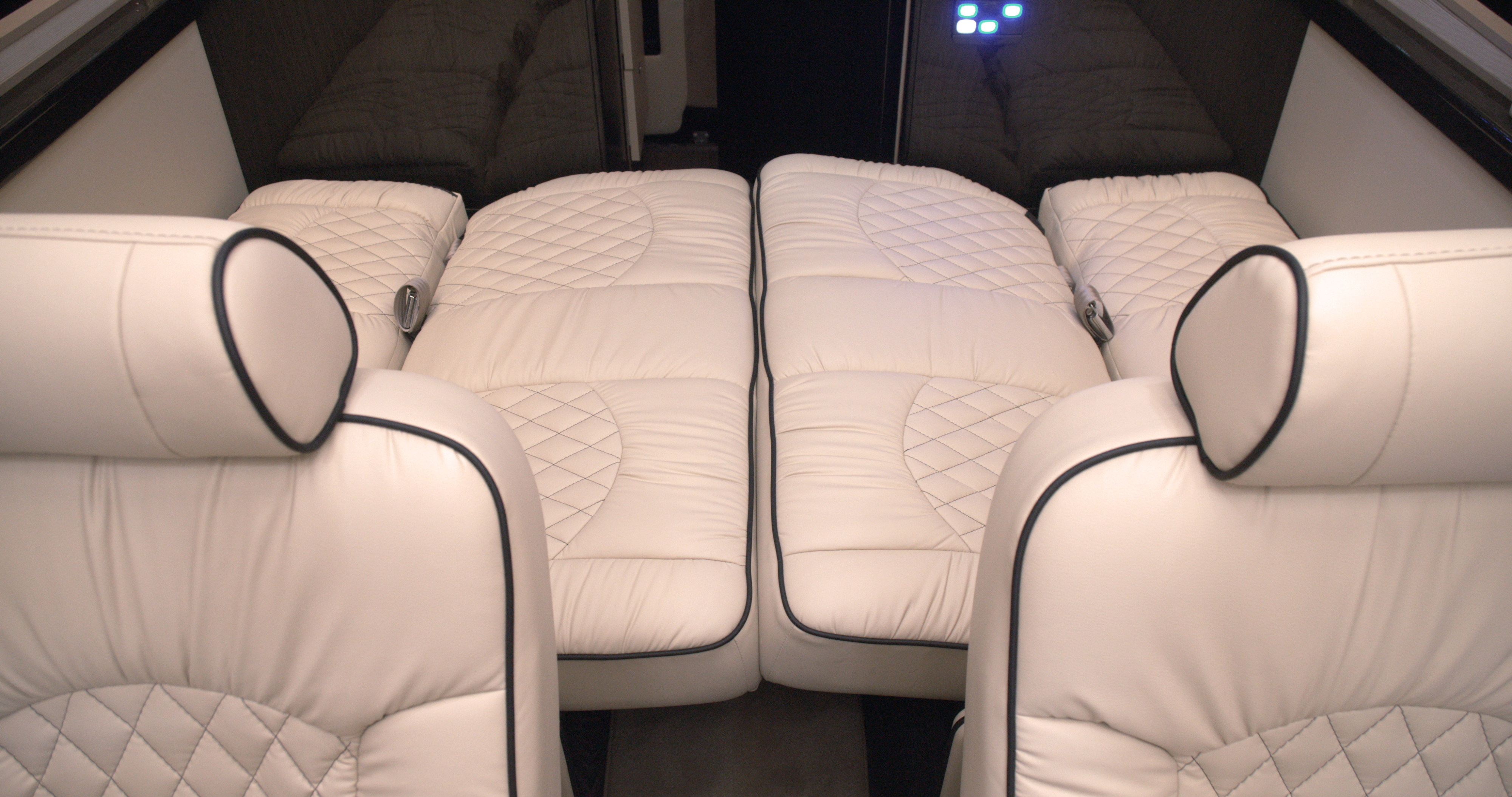Luxury RV rental interior featuring plush white quilted seats that convert to beds, ensuring comfort for your journey.. Mercedes Benz Sprinter 2023