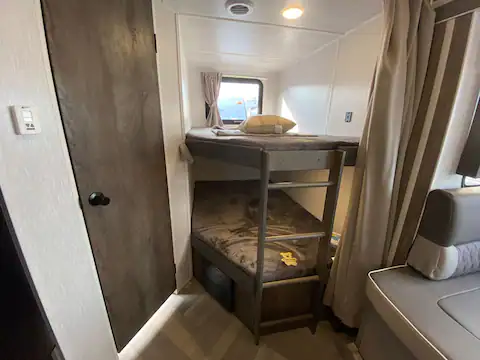 RV rental interior: cozy bunk beds with ladder, window, and adjacent seating. Ideal for comfortable family travel.. Forest River Salem Cruise Lite 2022