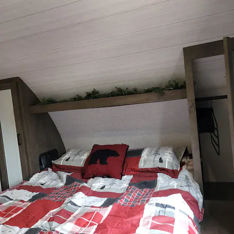 Cozy RV bedroom with red plaid bedding, a bear pillow, and wood paneling ceiling. Ideal for your RV rental journey.. Forest River Salem Cruise Lite 2022
