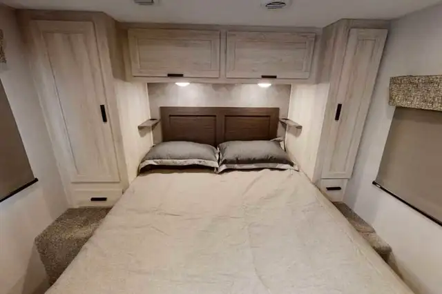 RV rental bedroom with bed, headboard, overhead cabinets, and side wardrobes for your travels.. Forest River Sunseeker LE 2021