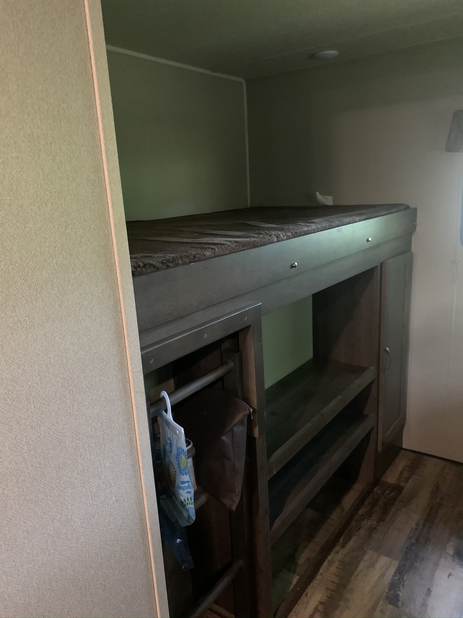 Interior of an rv rental showing a bunk bed with built-in storage shelves and a cabinet on a wood-look floor.. Forest River Palomino Puma 2017