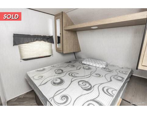 RV rental bedroom: patterned mattress, small window, and wooden overhead storage. Compact space for your travels.. Heartland RVs Prowler 2021