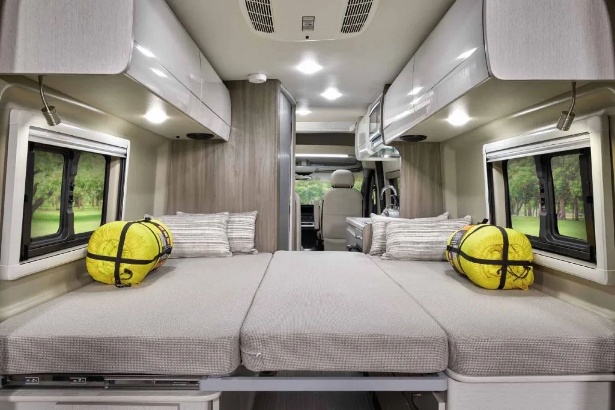 Spacious RV rental interior with convertible beds, overhead storage, and windows showing an outdoor view. Ideal for travel.. Dodge Thor 3500 2022