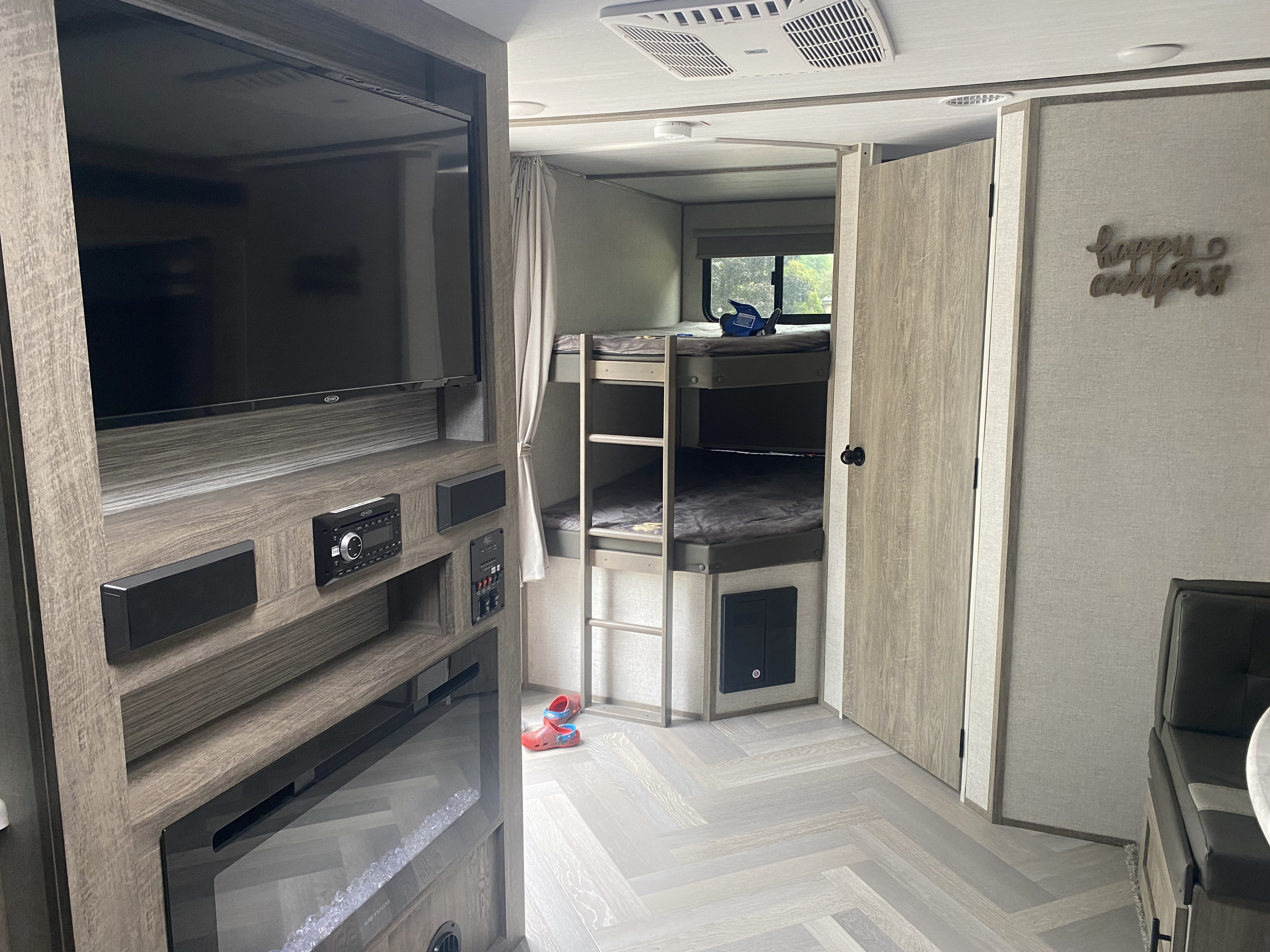 Spacious RV rental interior featuring a TV, entertainment center, bunk beds, and dining area, ideal for family trips.. Forest River Salem Hemisphere HL 2021