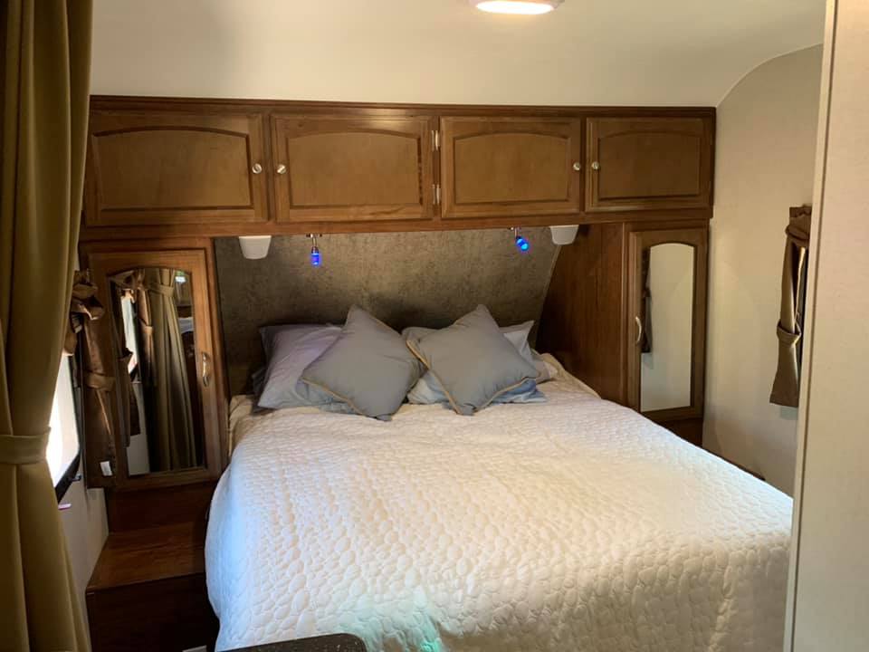 Inside a cozy RV rental: a comfortable bedroom with overhead cabinets, side wardrobes, and a quilted bedspread.. Coachmen Freedom Express 2016