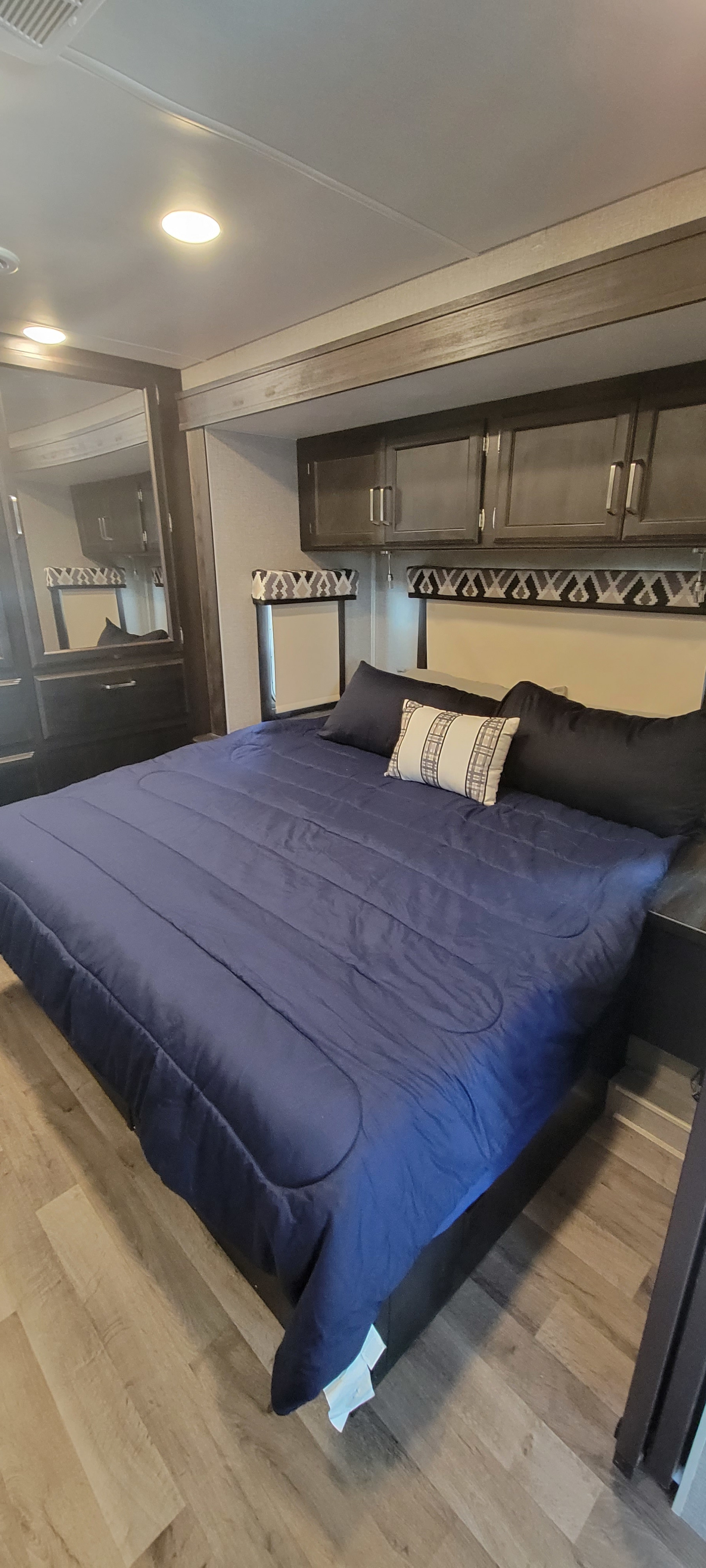 Cozy RV rental bedroom with queen bed, overhead storage, and mirrored wardrobe.. Jayco Greyhawk 2021