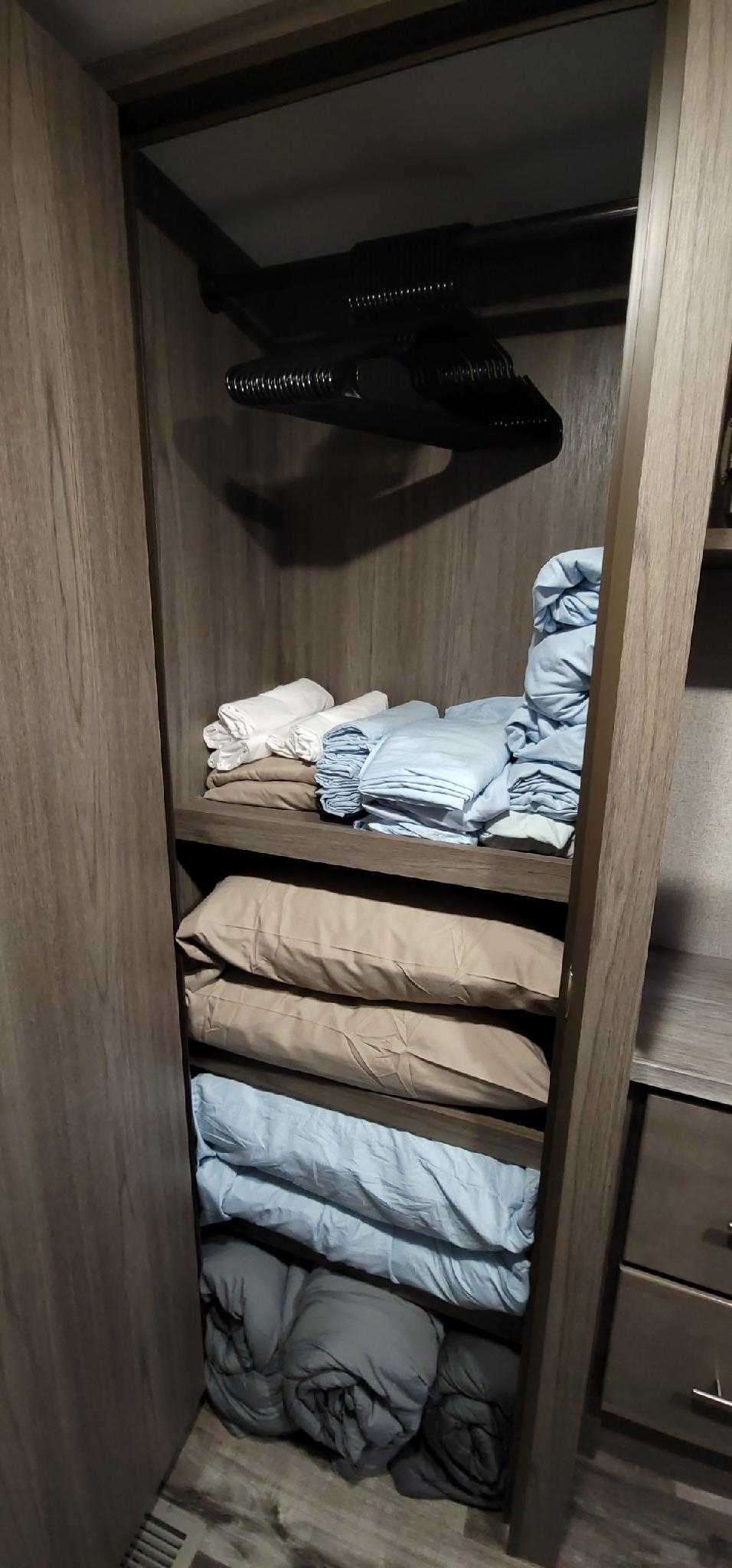 RV rental's organized closet features a hanging rod, shelves, and neatly folded linens and blankets.. Crossroads RV Volante HP 2022