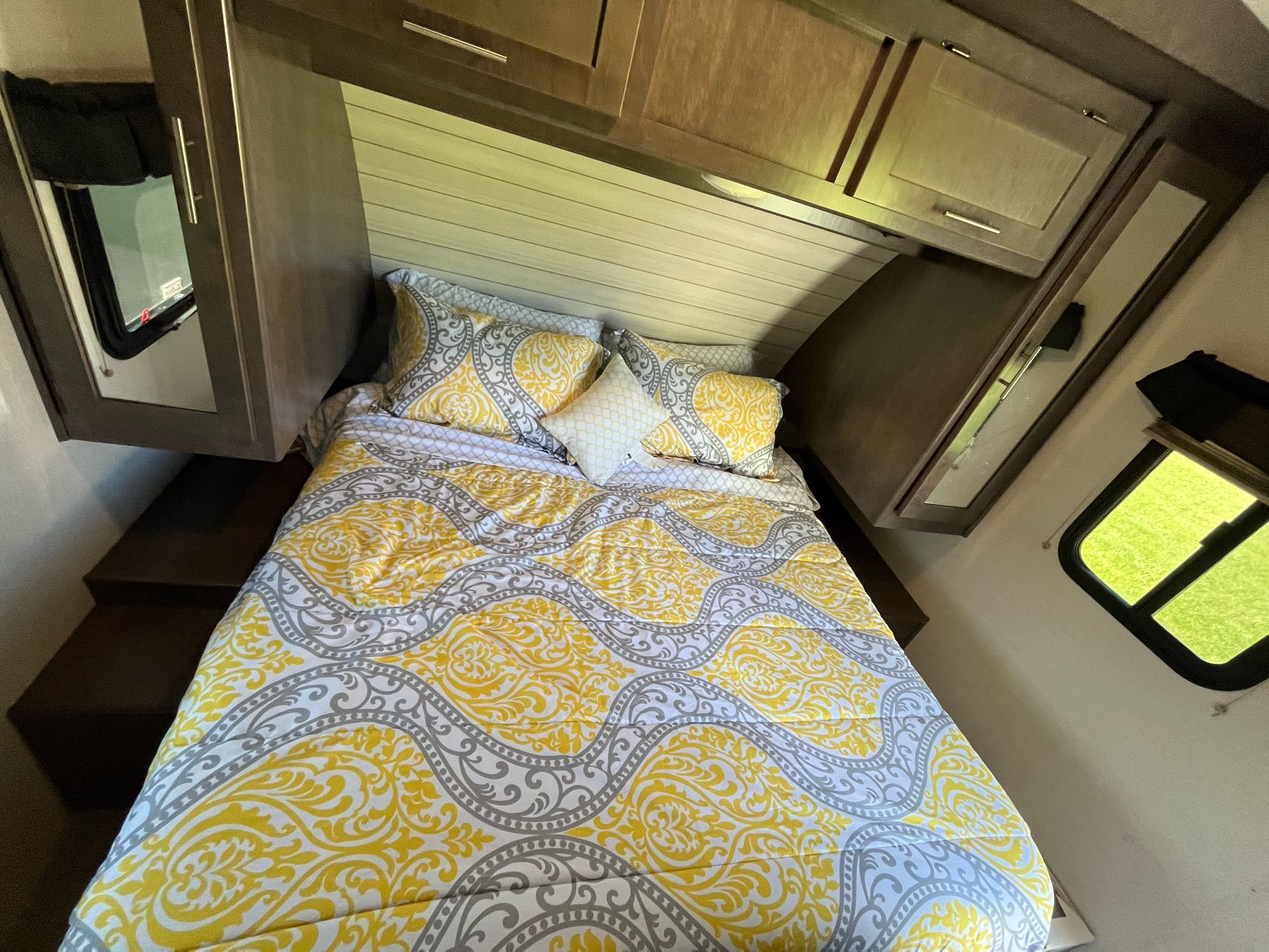 Cozy RV rental bedroom with a yellow and gray patterned bed, overhead cabinets, and convenient steps.. Crossroads RV Sunset Trail Super Lite 2018