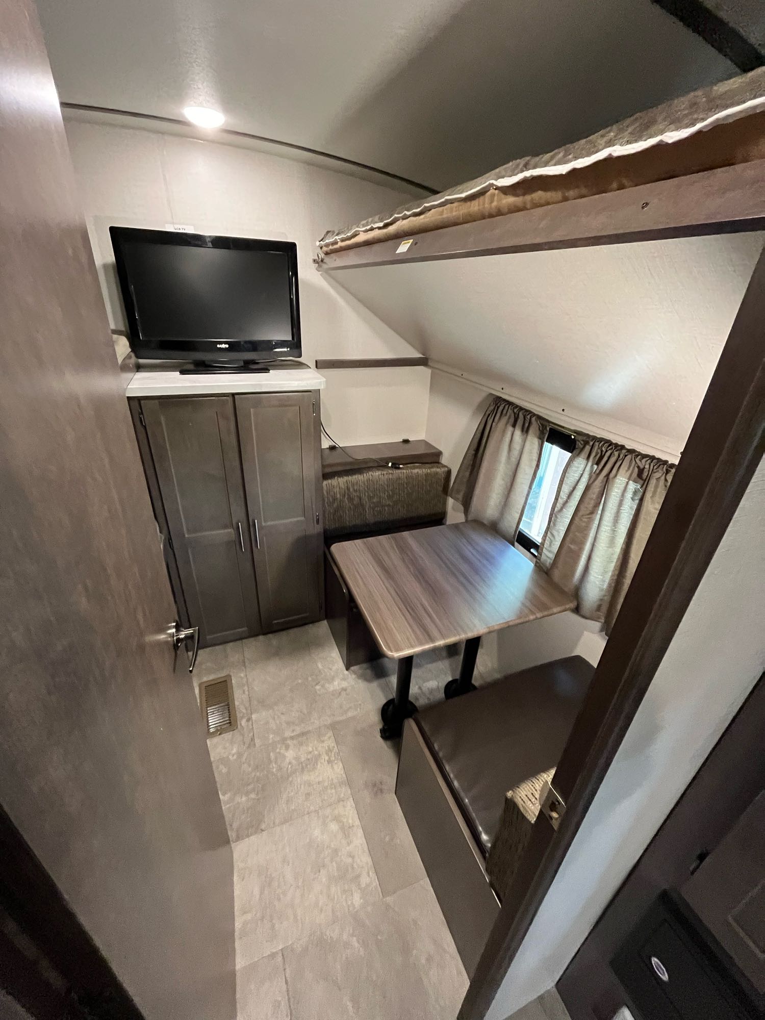 RV rental interior: cozy dinette with a bunk bed, TV, and storage, perfect for comfortable travel.. Crossroads RV Sunset Trail Super Lite 2018