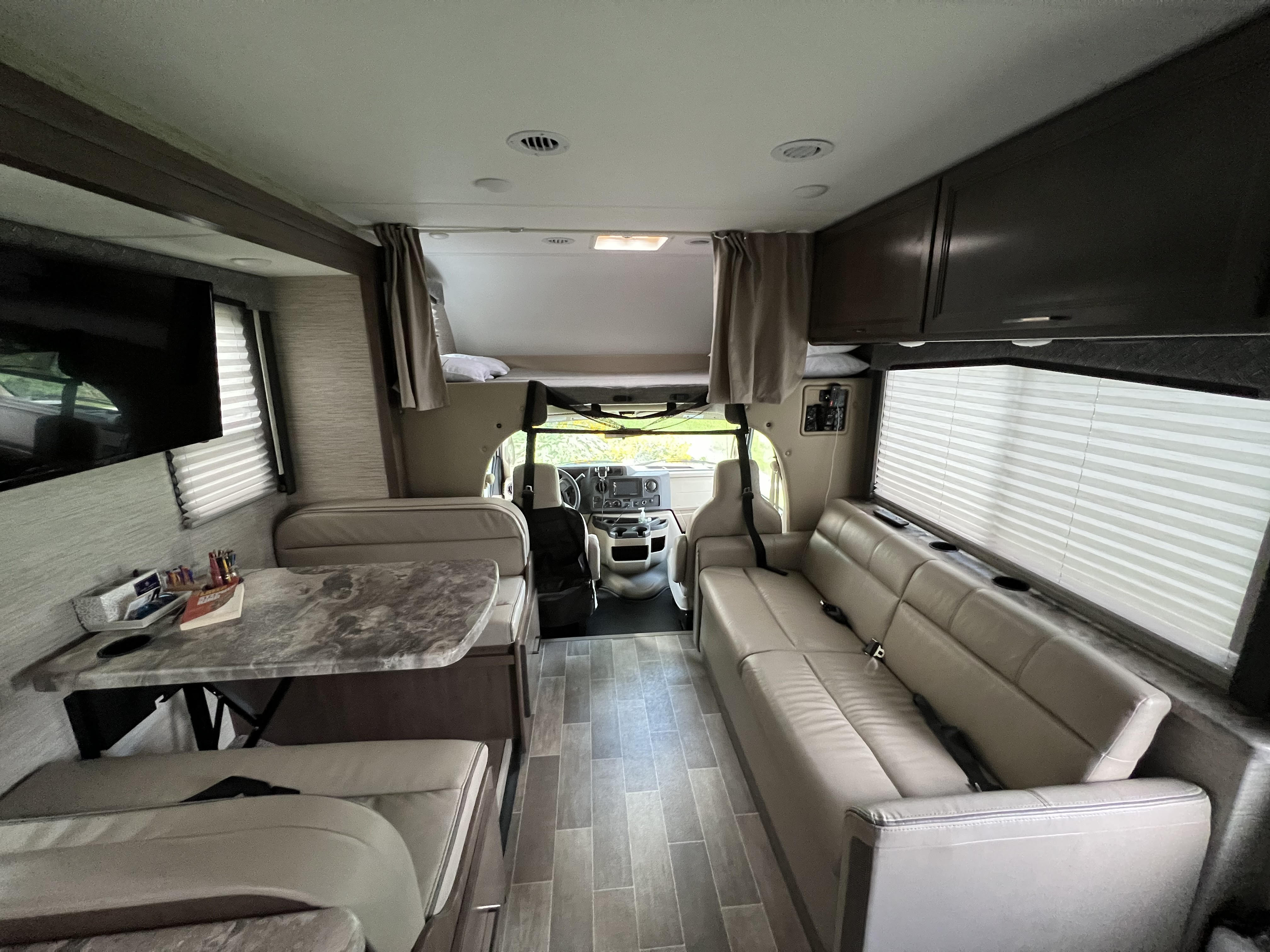 Spacious rv rental interior with a dinette, comfy sofa, and overhead bunk, ready for adventures.. Thor Chateau 2022