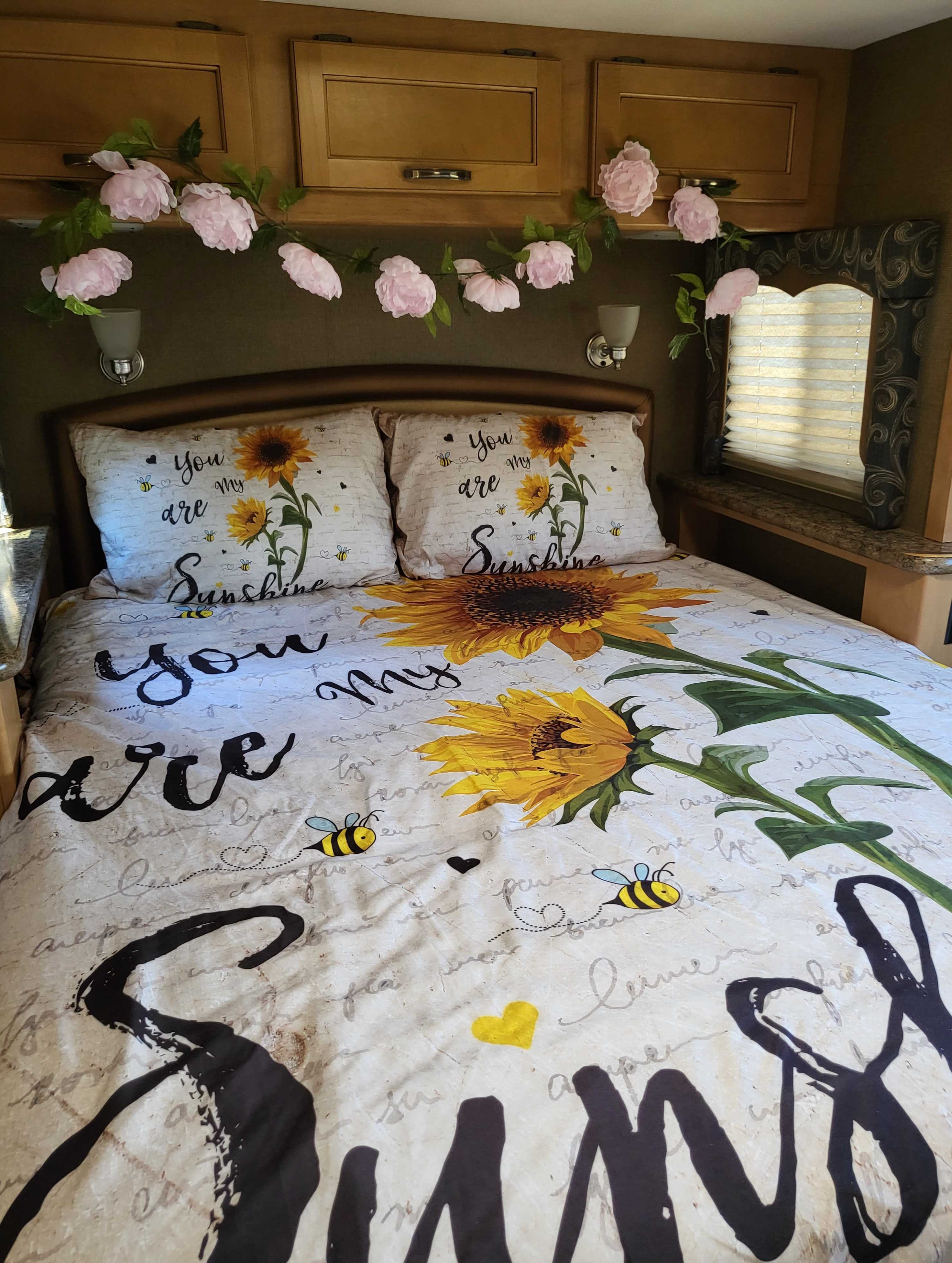 Cozy RV rental bedroom with "You are my sunshine" sunflower bedding and floral garland, perfect for a cheerful camper getaway.. Thor Four Winds 2016