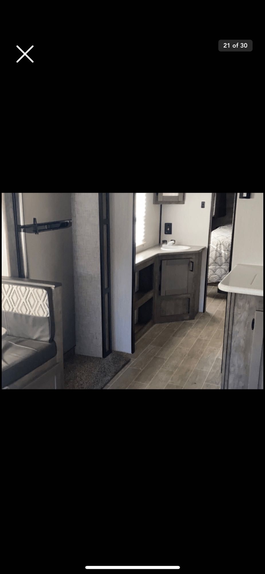 Modern RV rental interior with comfortable seating, a compact sink area, and a private bedroom beyond.. Heartland RVs Wilderness 2020