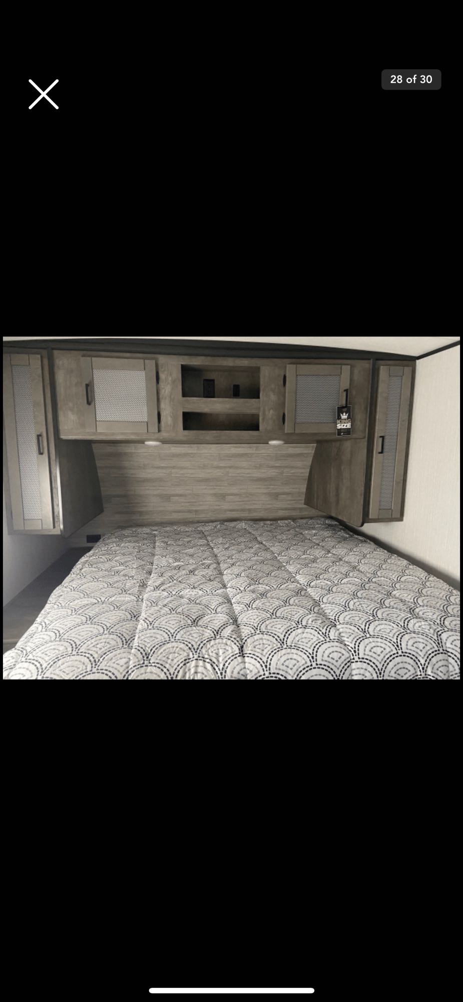 Spacious RV rental bedroom with a king bed, built-in storage, and modern gray wood accents.. Heartland RVs Wilderness 2020