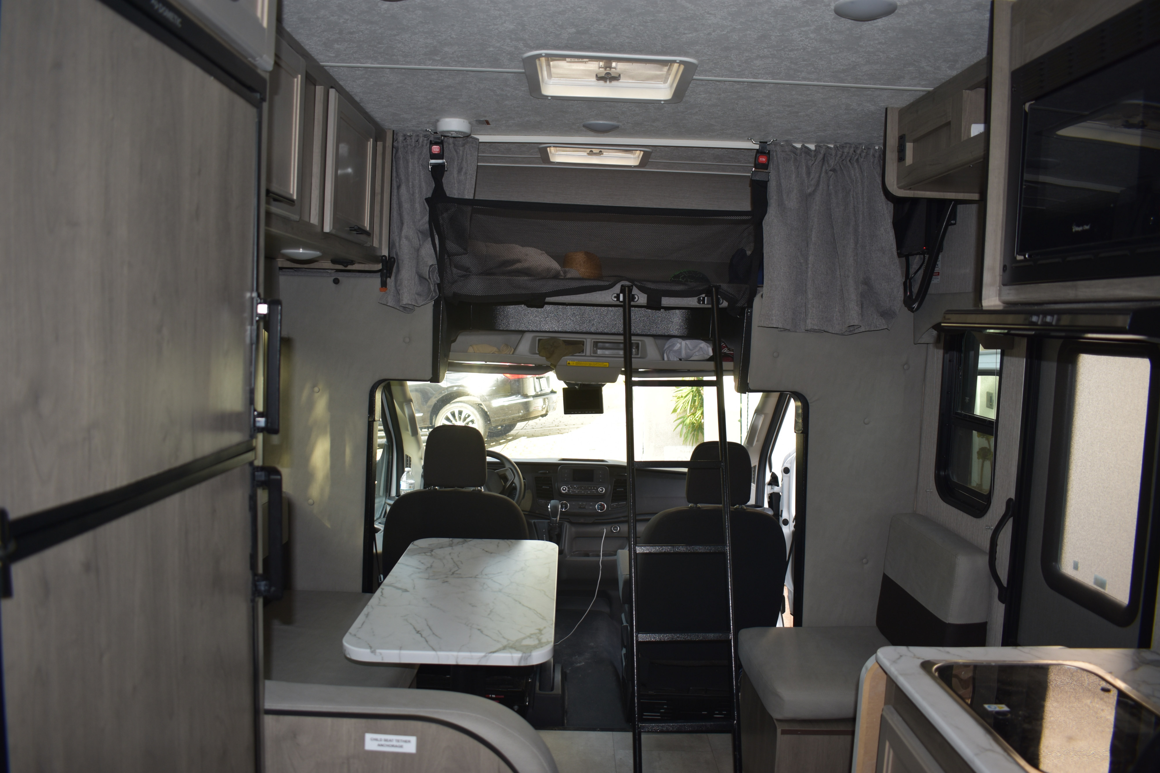 Interior of an RV rental showing the dining table, kitchen, bunk bed with ladder, and front cockpit. Ideal for travel.. Coachmen Cross Trail 20CB 2022