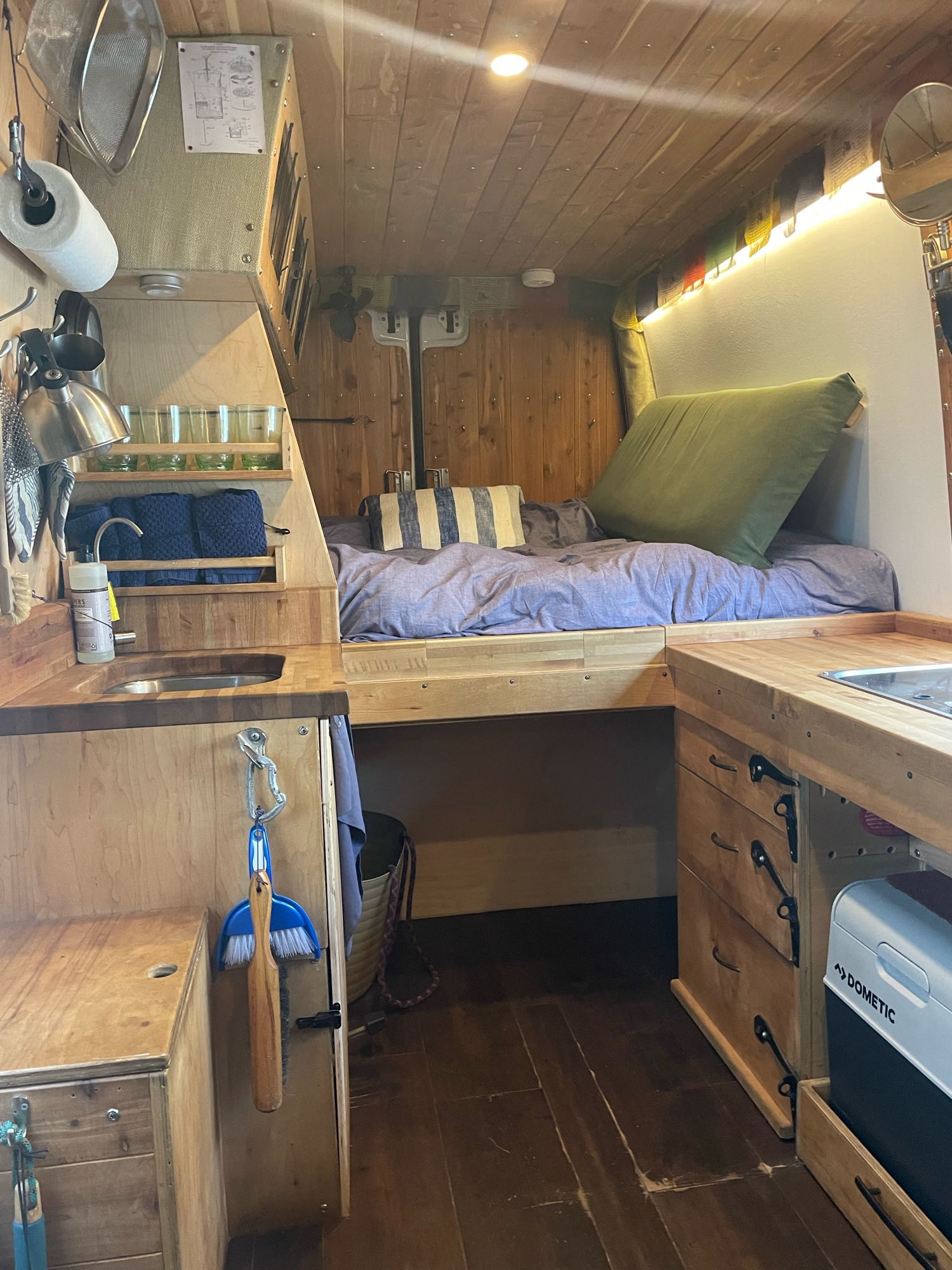 Cozy RV rental interior: custom wood-paneled campervan with bed, kitchen, & clever storage for mobile living.. Mercedes-Benz Sprinter 2016