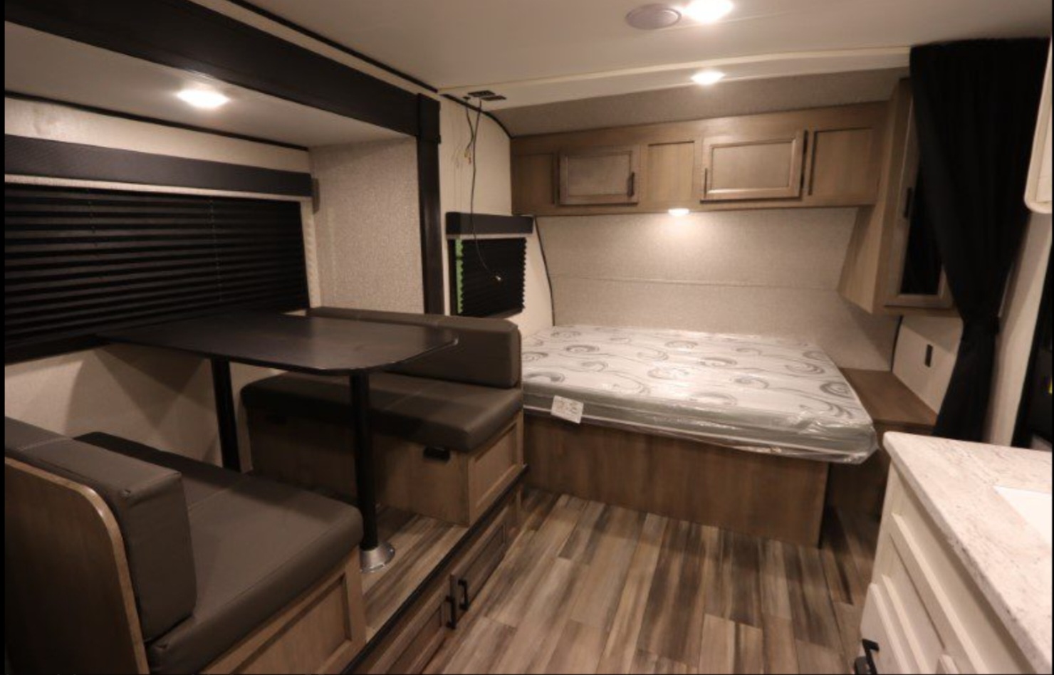 Modern rv rental interior featuring a dinette, comfortable bed with overhead storage, and a small kitchen area.. Highland Ridge RV Open Range 2022