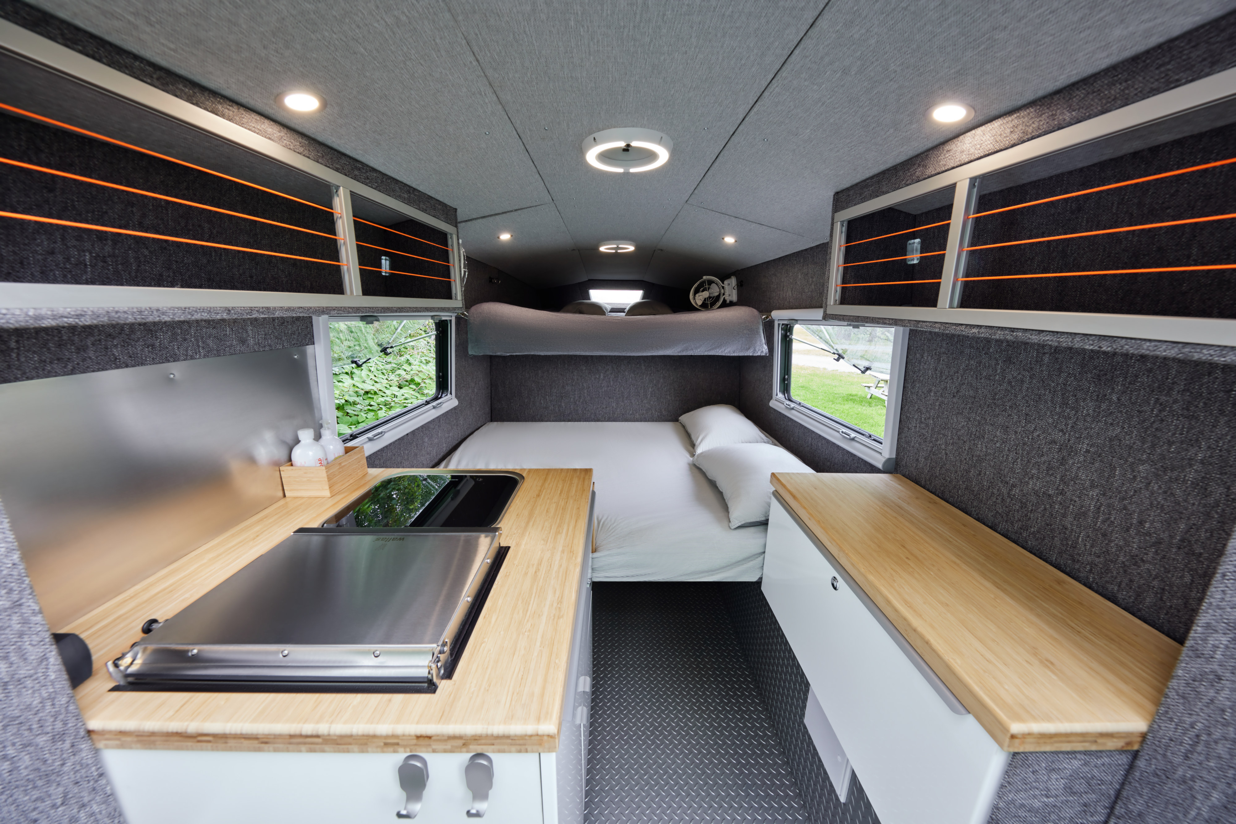 Step inside this RV rental's cozy interior, featuring a comfortable bed, compact kitchen with cooktop, and clever overhead storage.. Chevrolet silverado 2500 2022