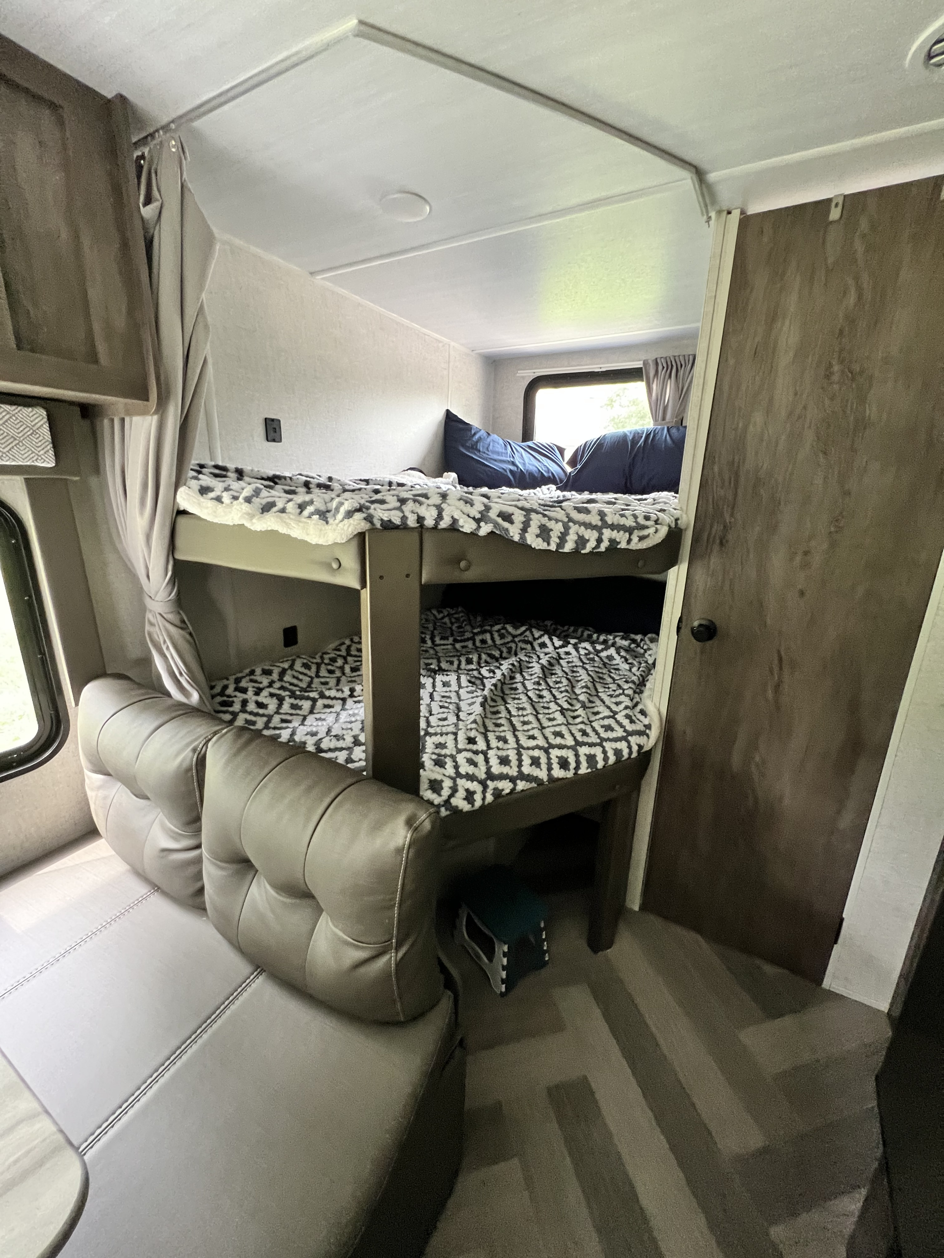 Cozy RV rental interior with bunk beds, soft blankets, and comfortable dinette seating for family travel.. Forest River Salem Cruise Lite 2021