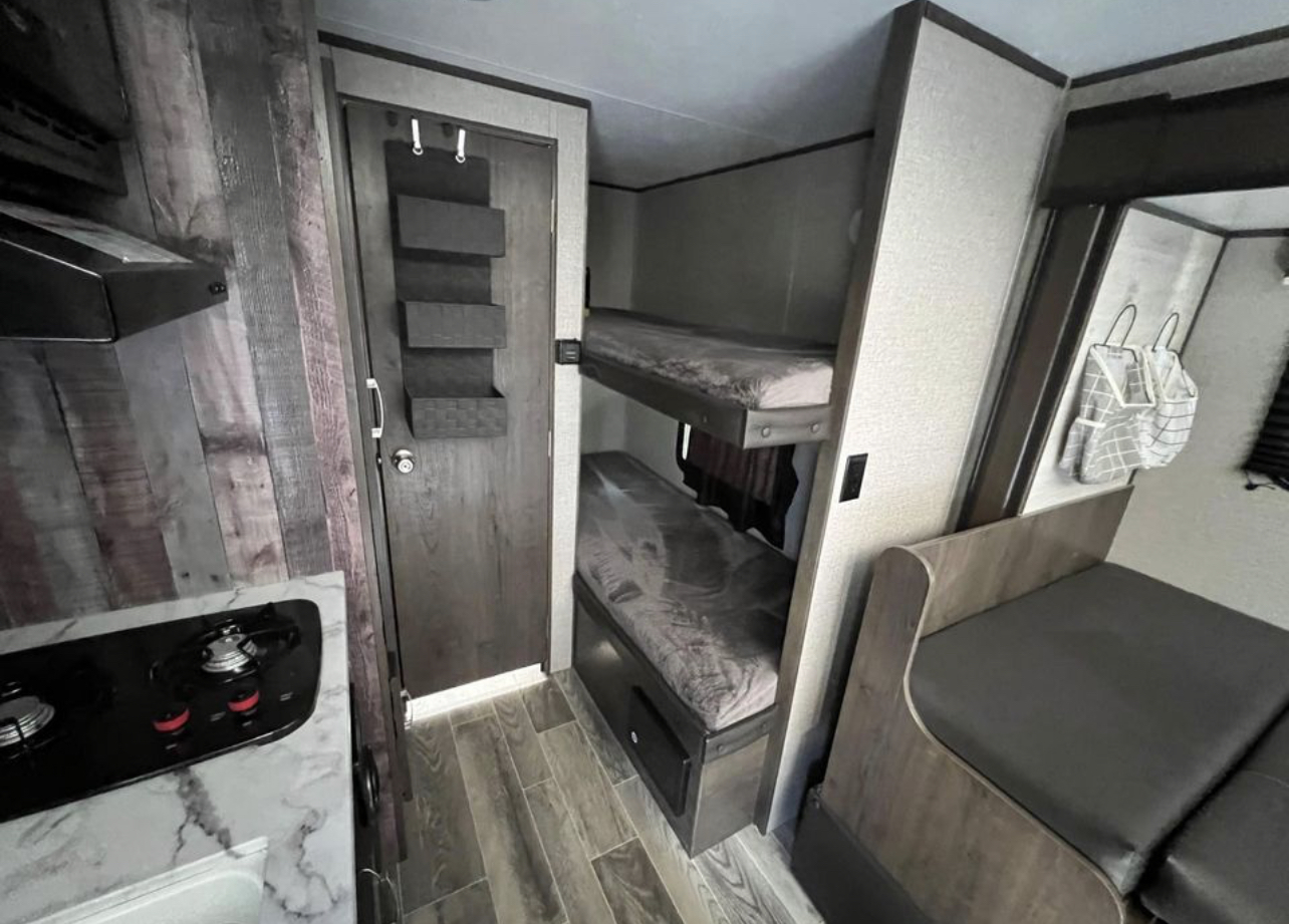 Inside an RV rental: features a kitchen with stove, bunk beds, and dinette area with storage for a cozy and functional living space.. Jayco Jay Flight SLX Baja Edition 2021