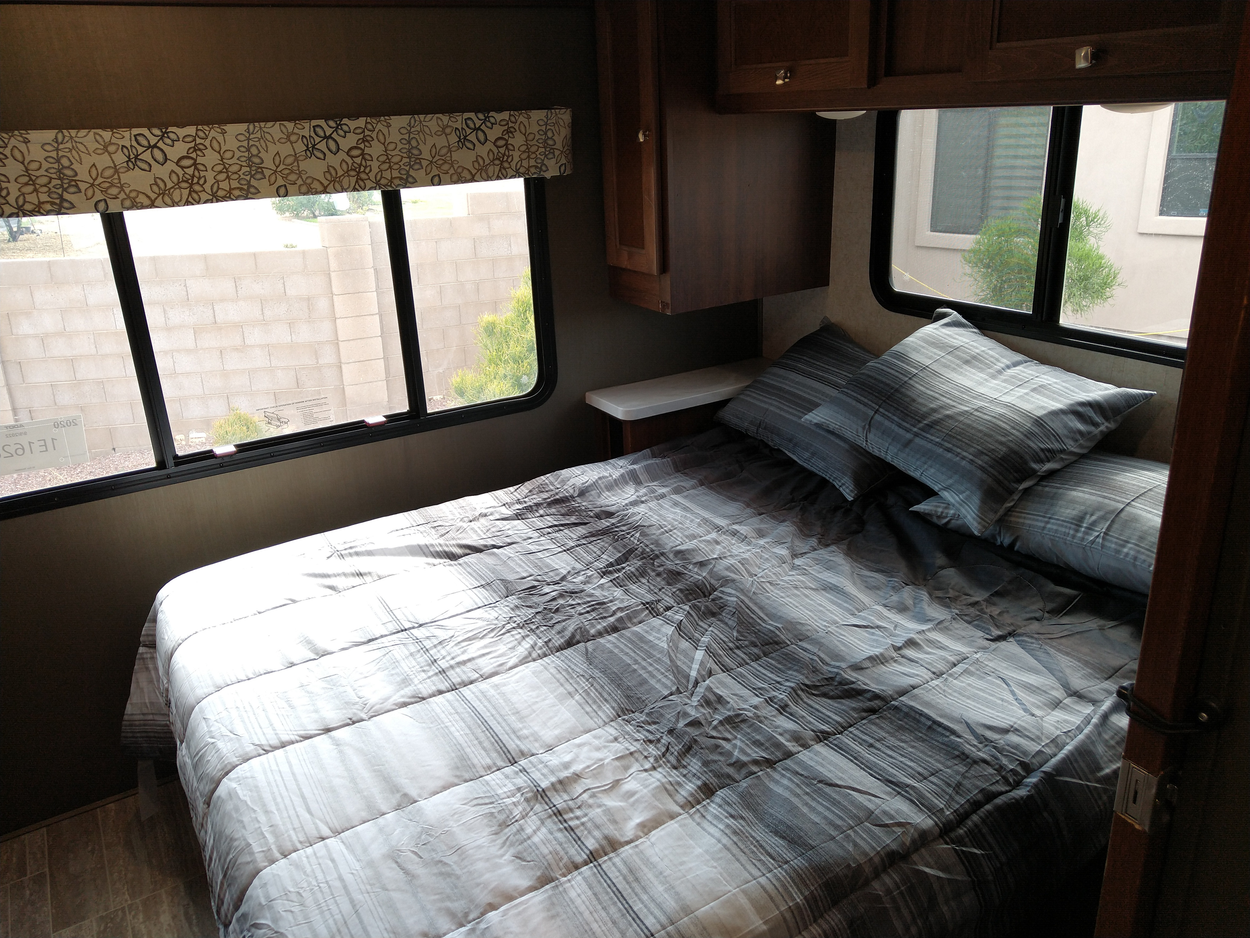 RV rental bedroom: comfy bed with striped bedding, pillows, and windows offering an outside view.. Forester LE 2020