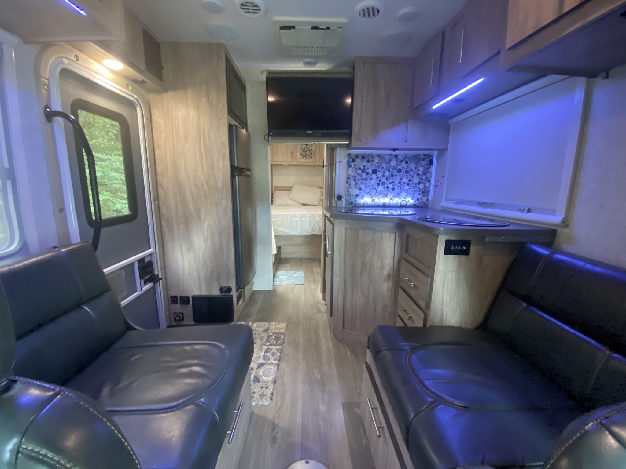 Spacious RV rental interior with black leather seating, a modern kitchen, and bedroom amenities for comfortable travel.. Forest River Sunseeker 2017