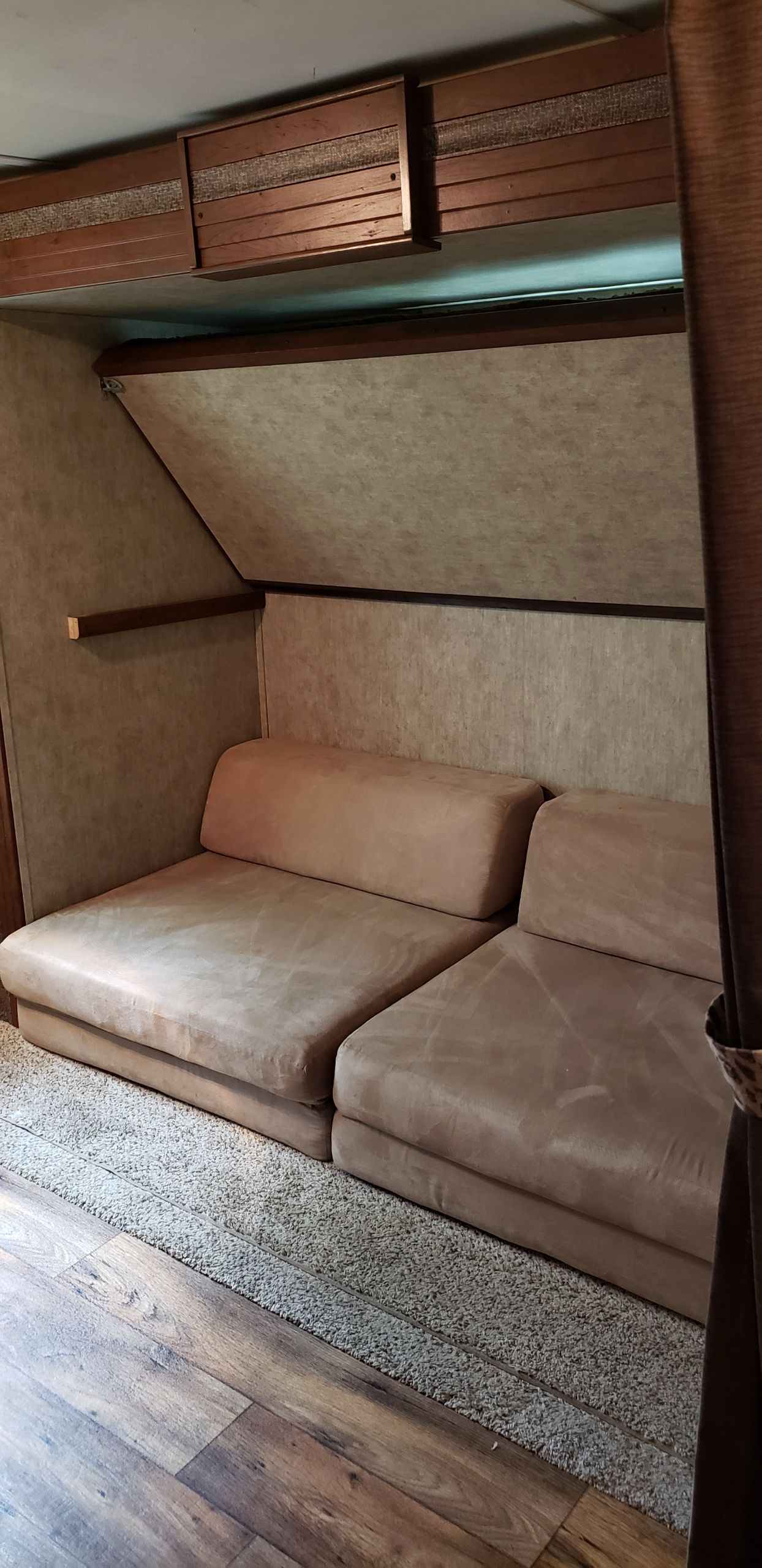 Inside an RV rental: plush floor cushions, overhead cabinets, and a blend of carpet and wood flooring.. Keystone RV Passport Grand Touring 2016